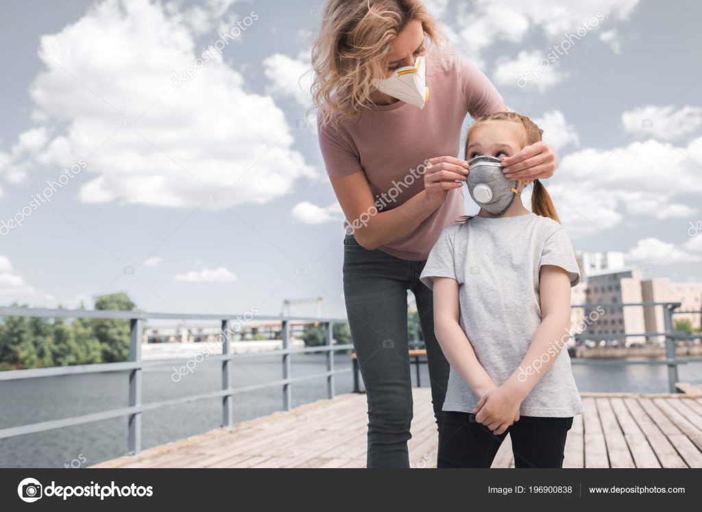 Mother and daughter in protective masks on bridge, air pollution concept – stock image