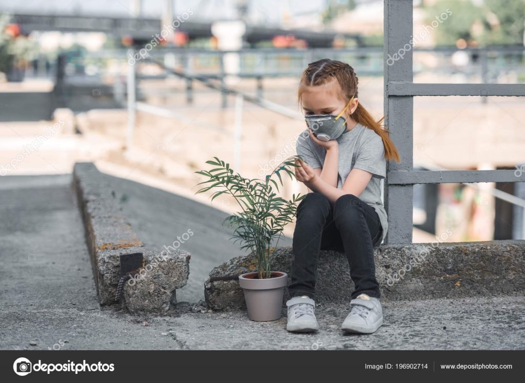 Child in protective mask looking at green potted plant, air pollution concept – stock image