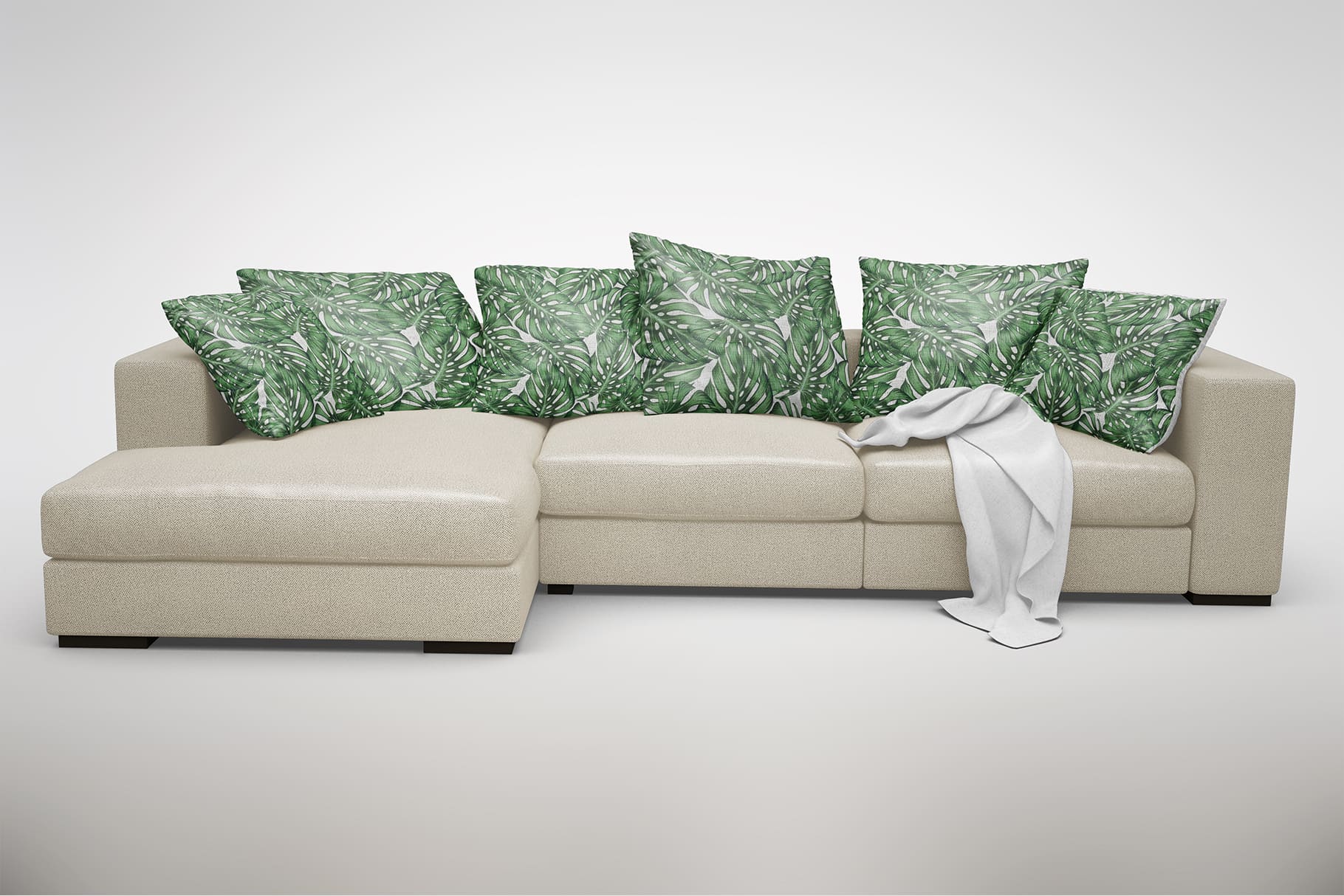 Large beige corner sofa with decorative cushions depicting a green leaf.