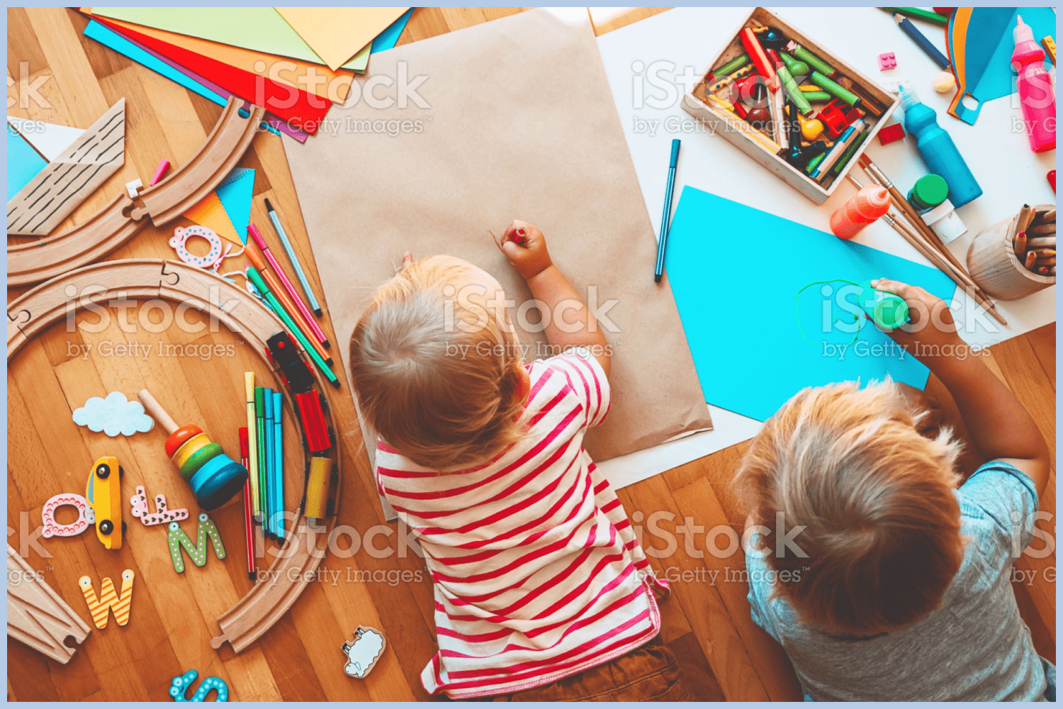 Two kids are drawing with pencils.