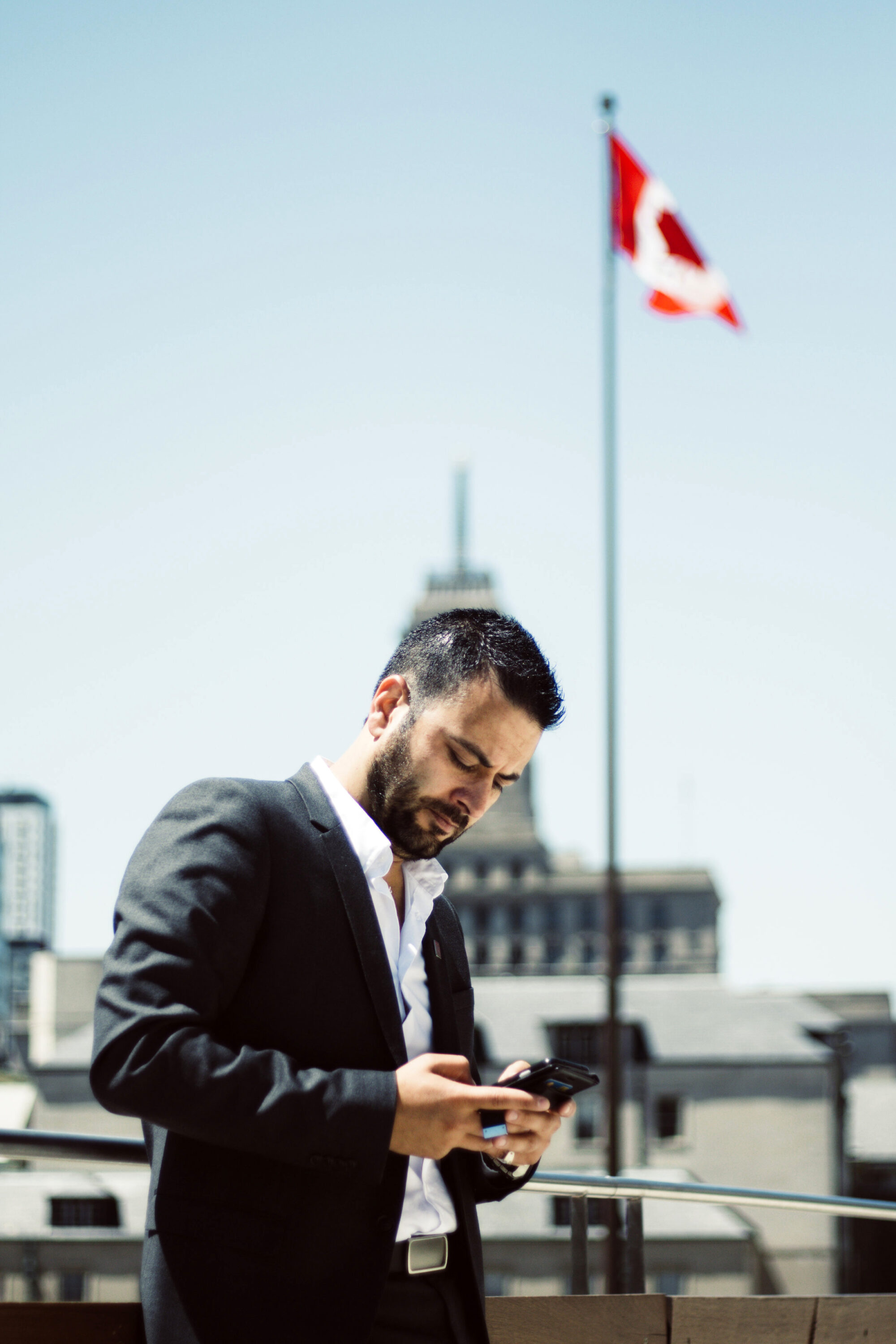 Man standing under a flag working on a cellphone.