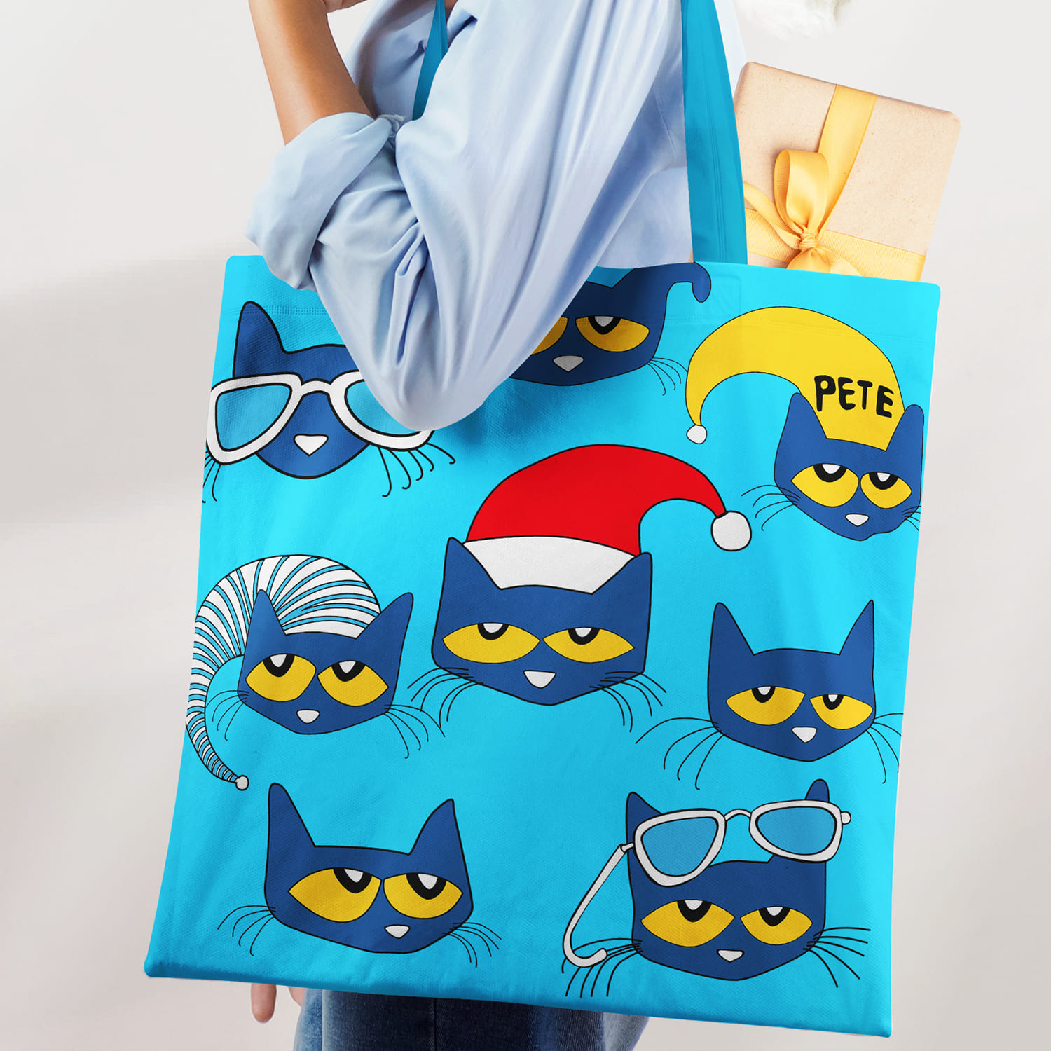 Woman holding a blue bag with cats on it.