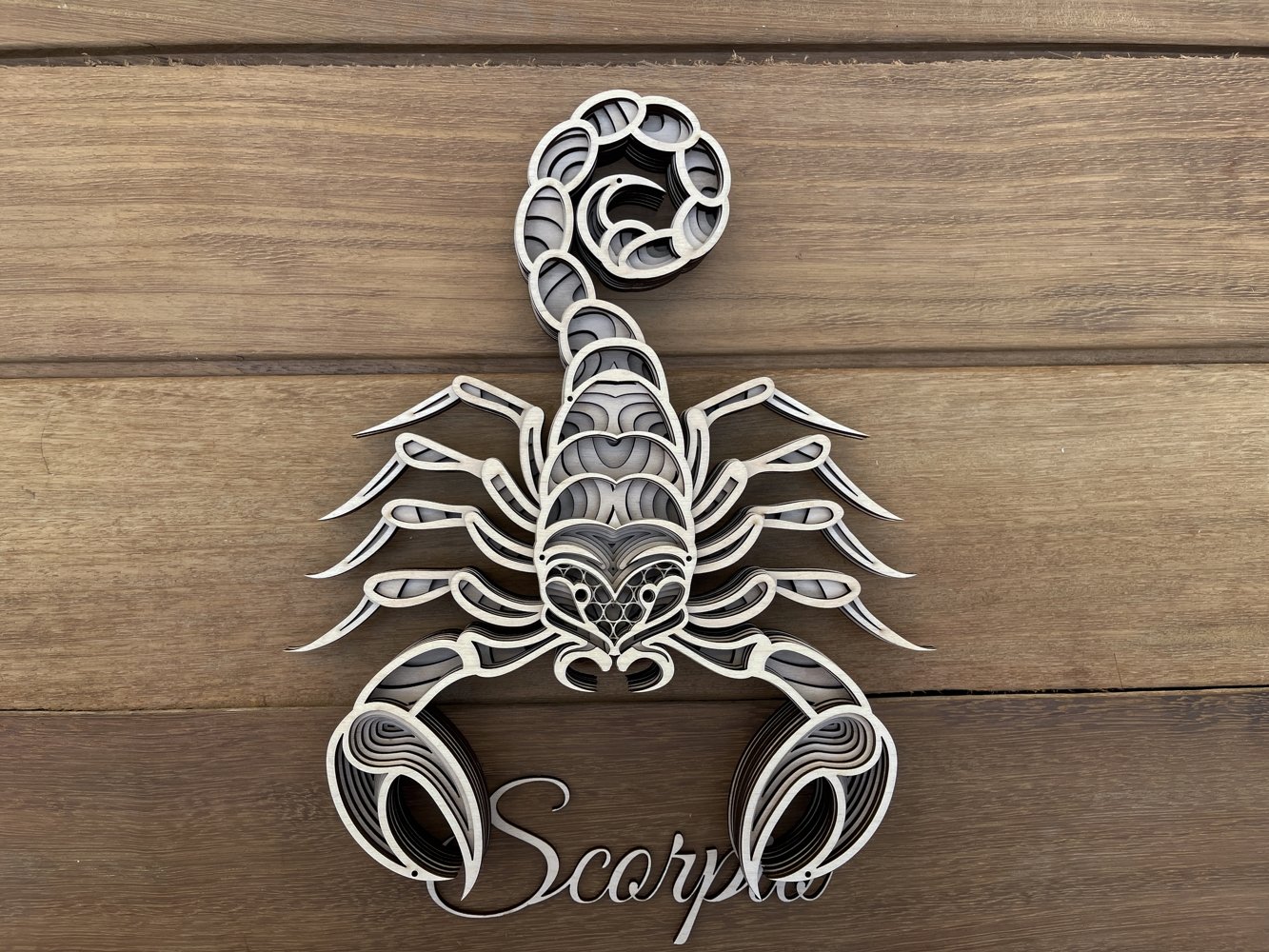Metal scorpion on a wooden surface.
