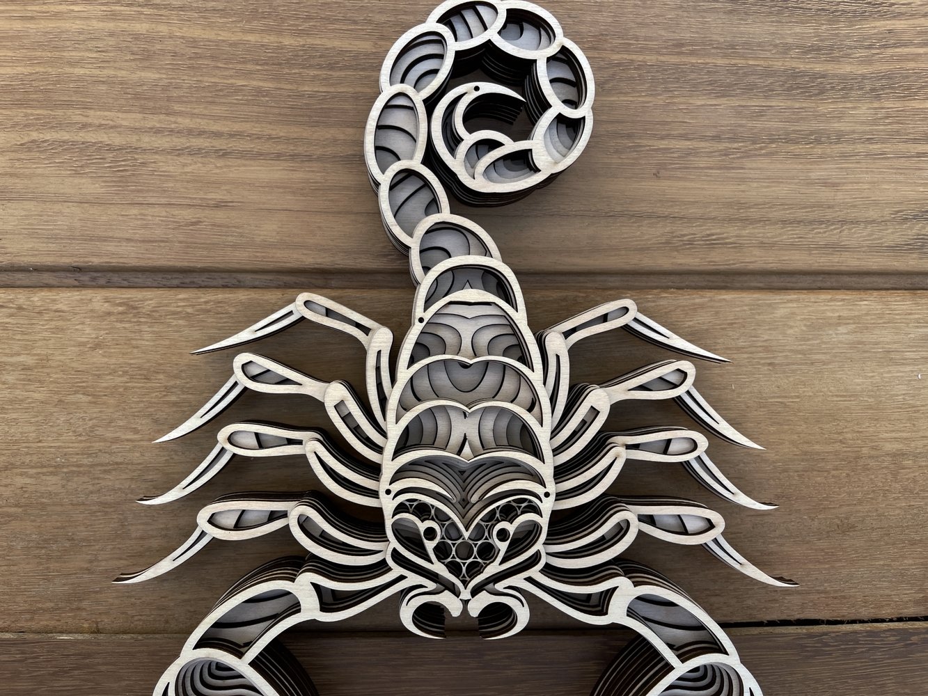 Metal sculpture of a scorpion on a wooden surface.