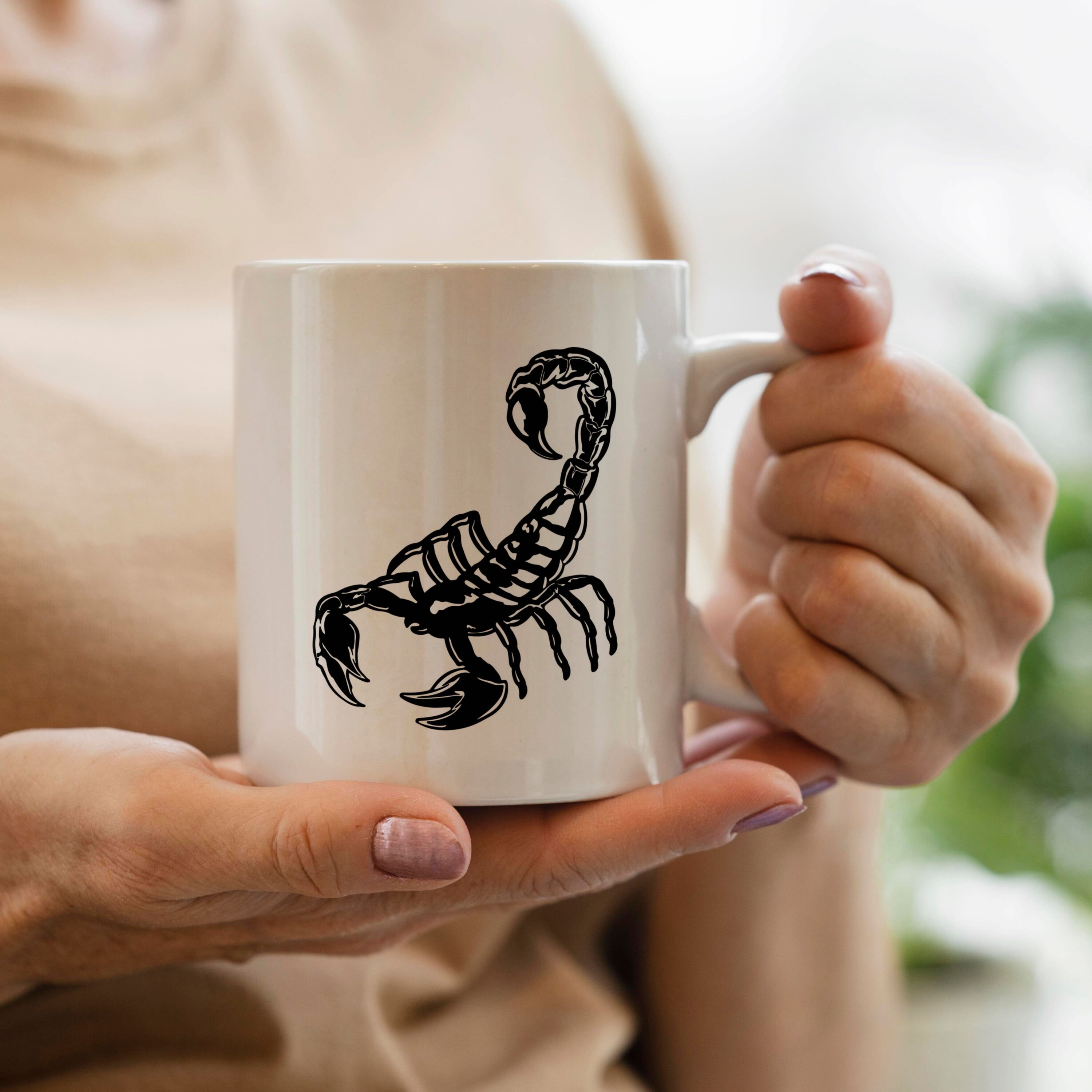 Woman holding a coffee mug with a scorpion on it.