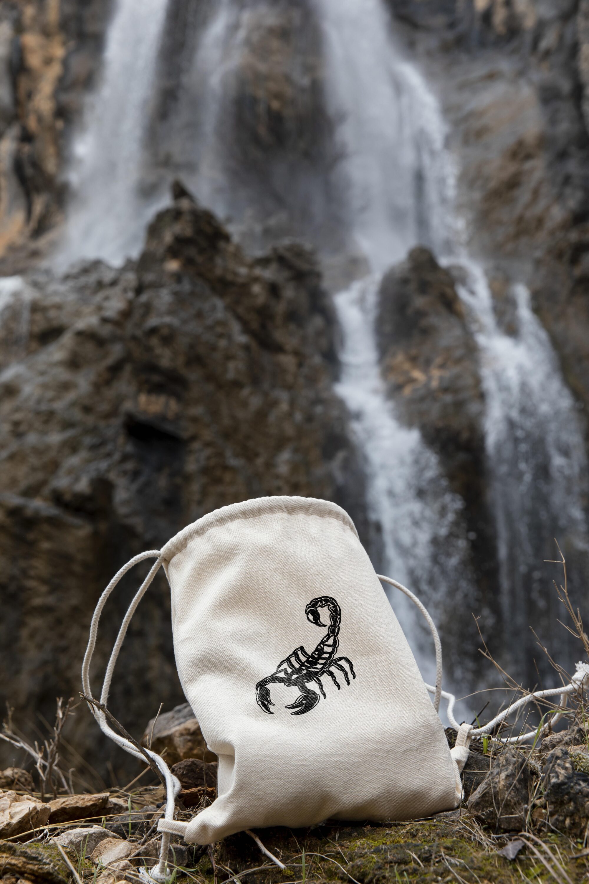 Bag sitting on the ground in front of a waterfall.