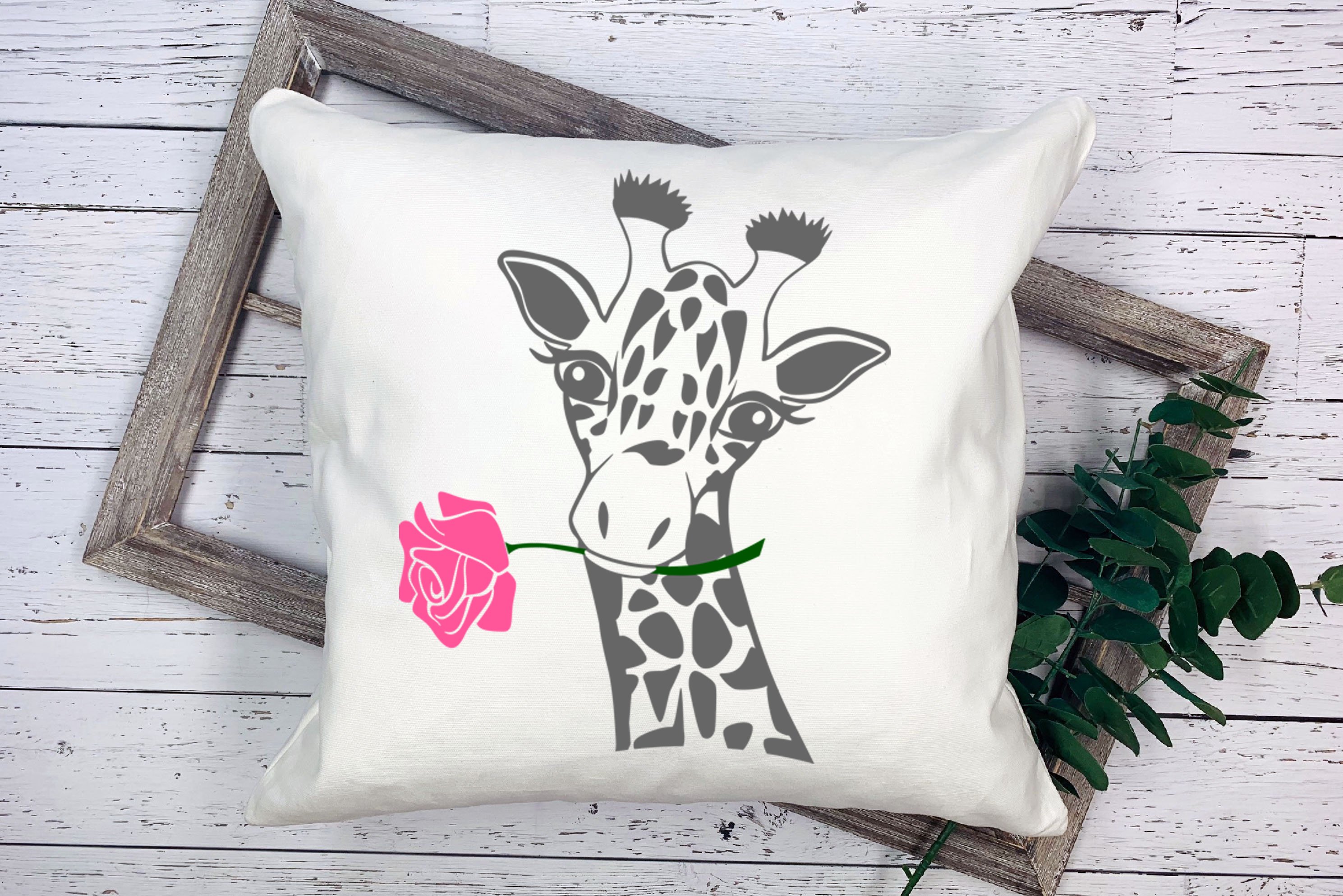 Pillow with a giraffe and a rose on it.