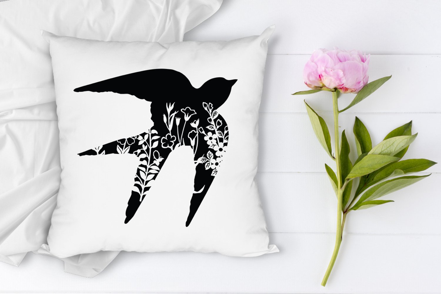White pillow with a black bird on it.