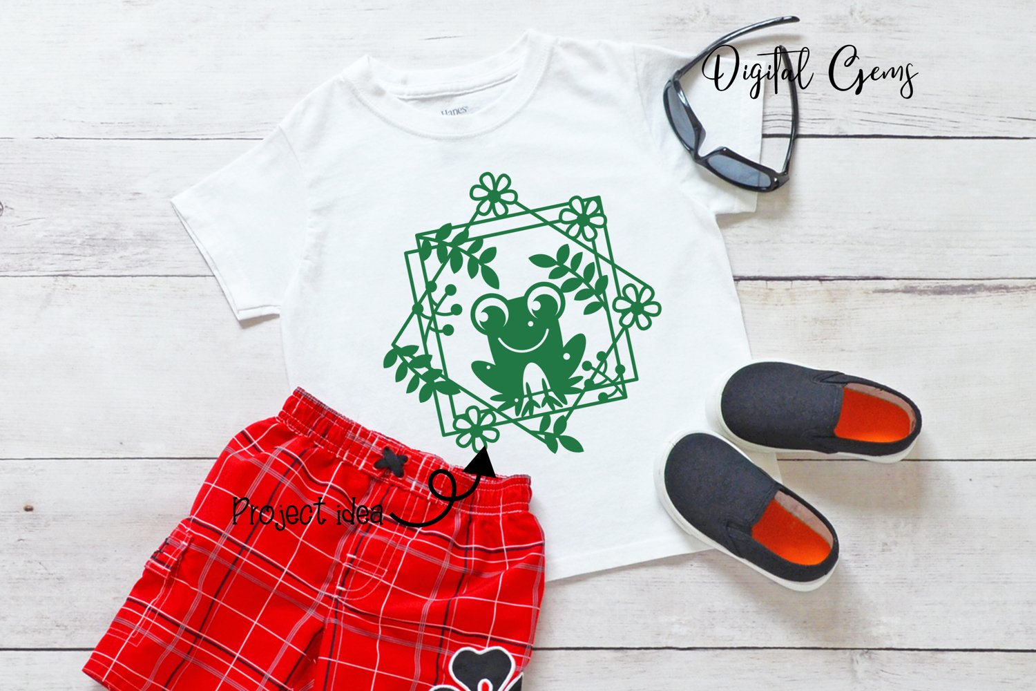 White shirt with a green frog on it next to a pair of red shorts.