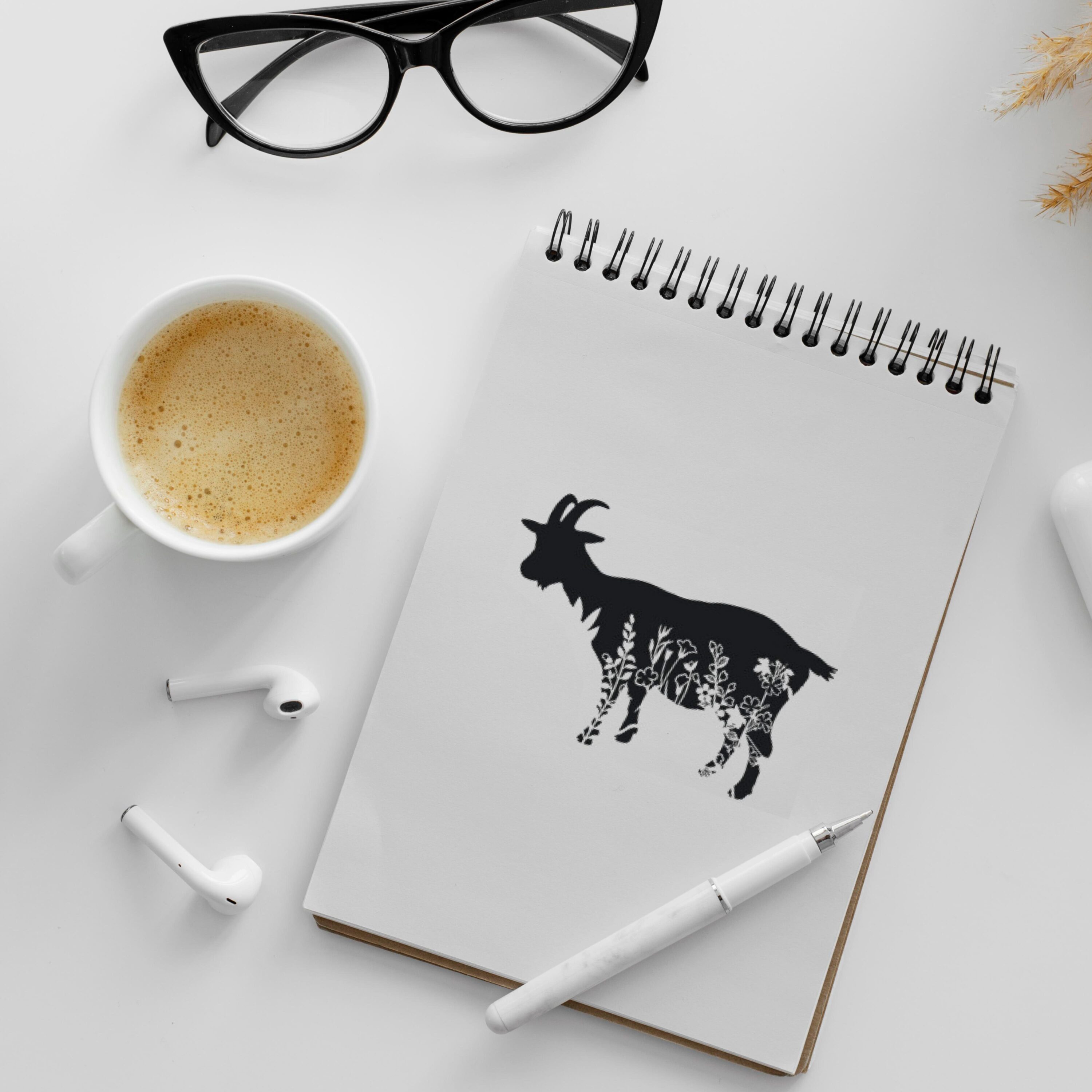 Notebook with a goat drawn on it next to a cup of coffee.