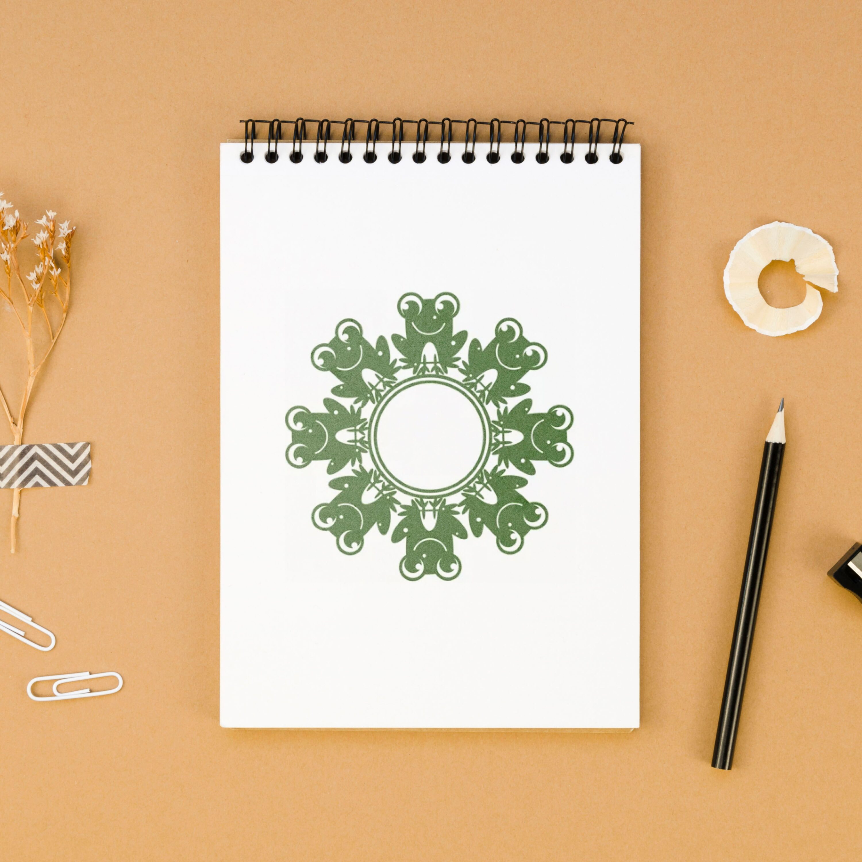 Spiral notebook with a green design on it.