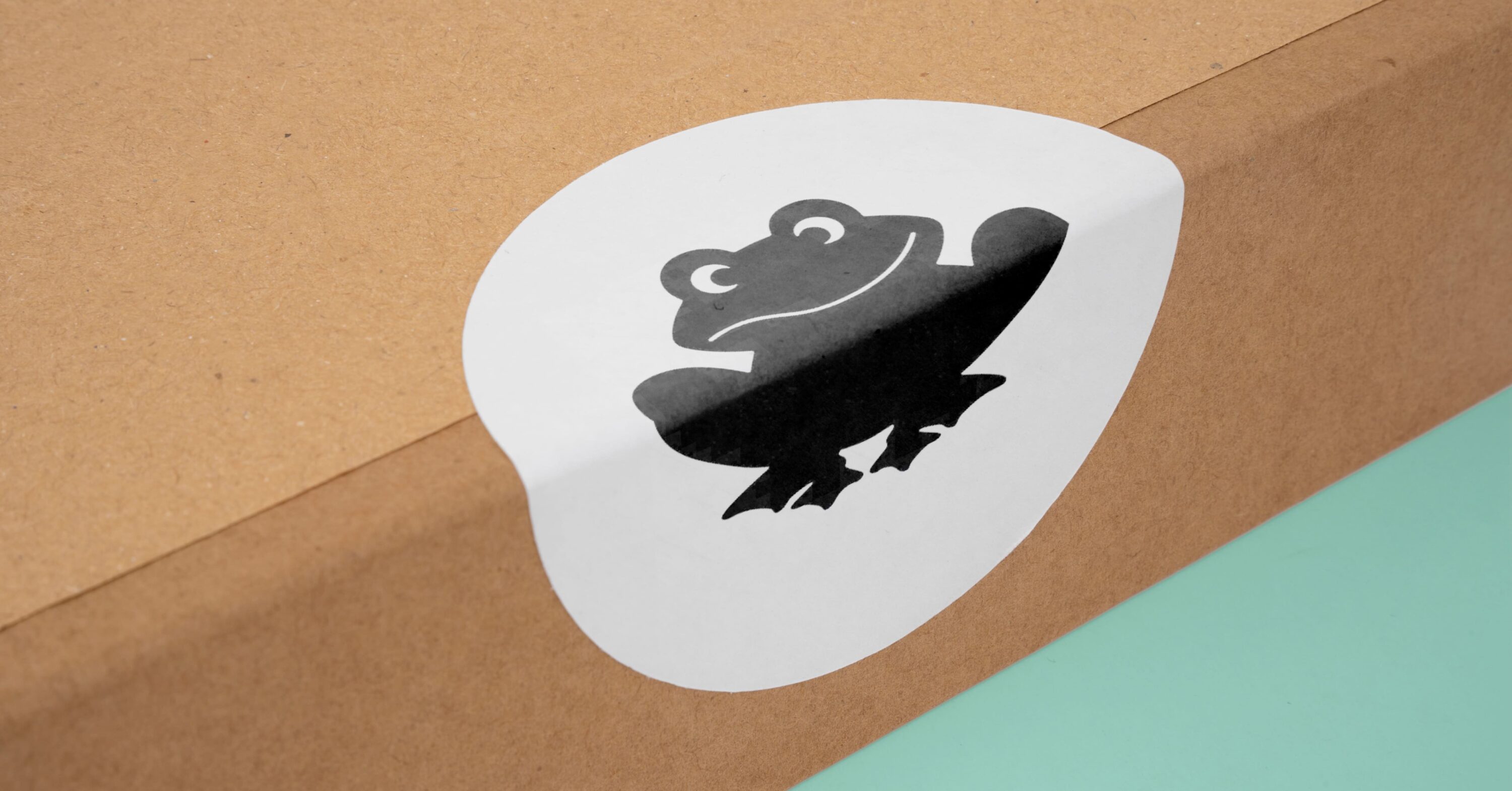 Frog sticker on the side of a cardboard box.