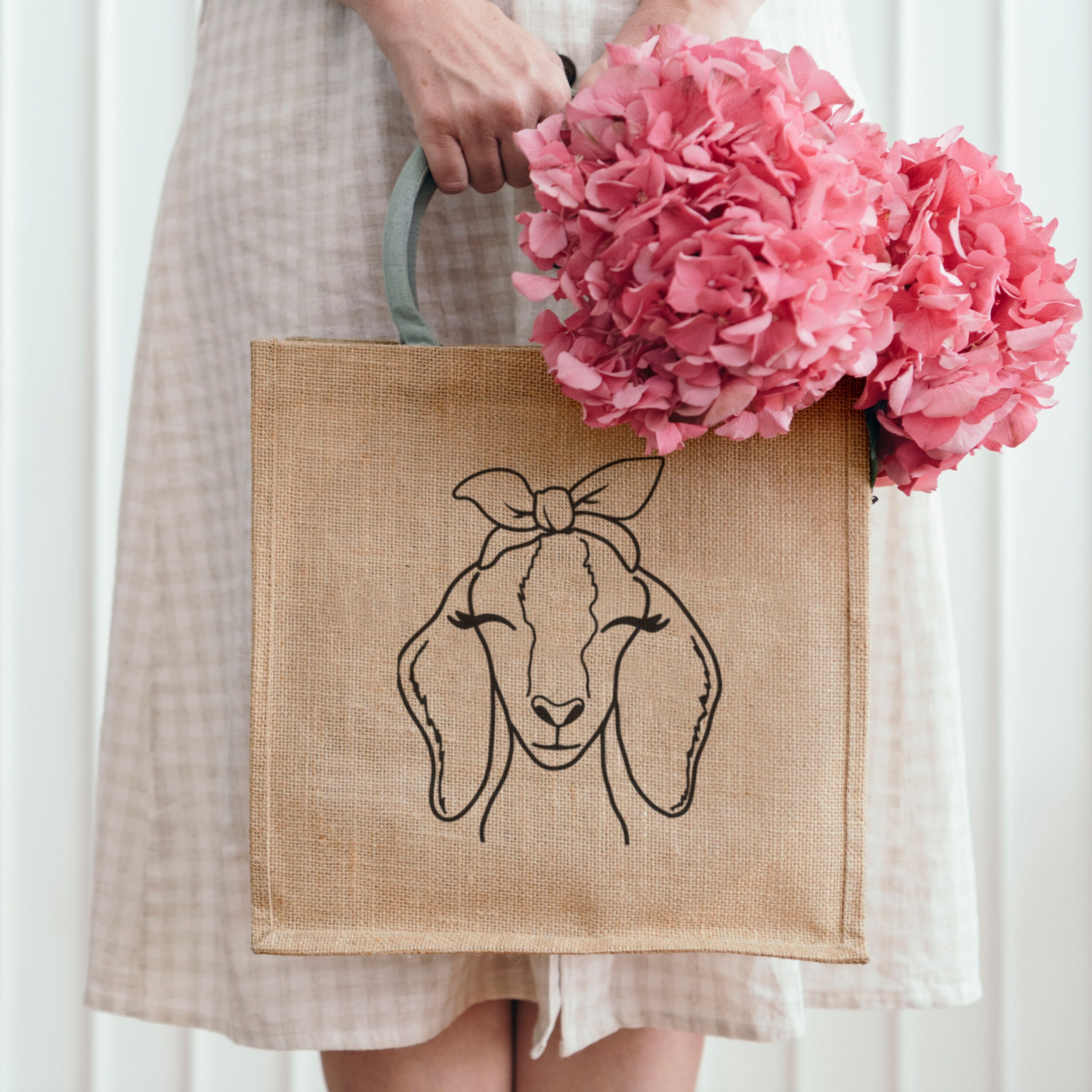 Woman holding a bag with a picture of a sheep on it.