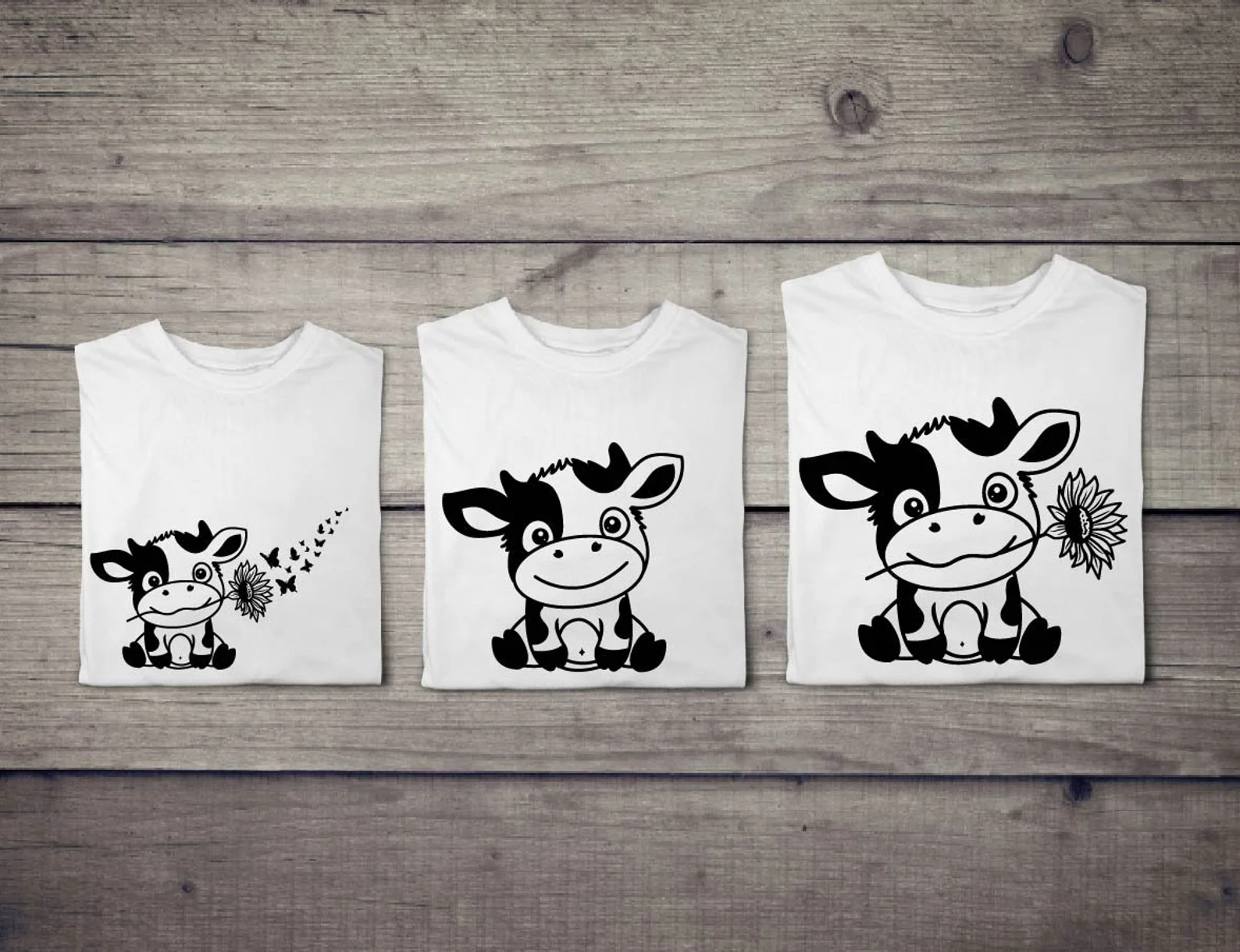Three t - shirts with a cartoon cow on them.