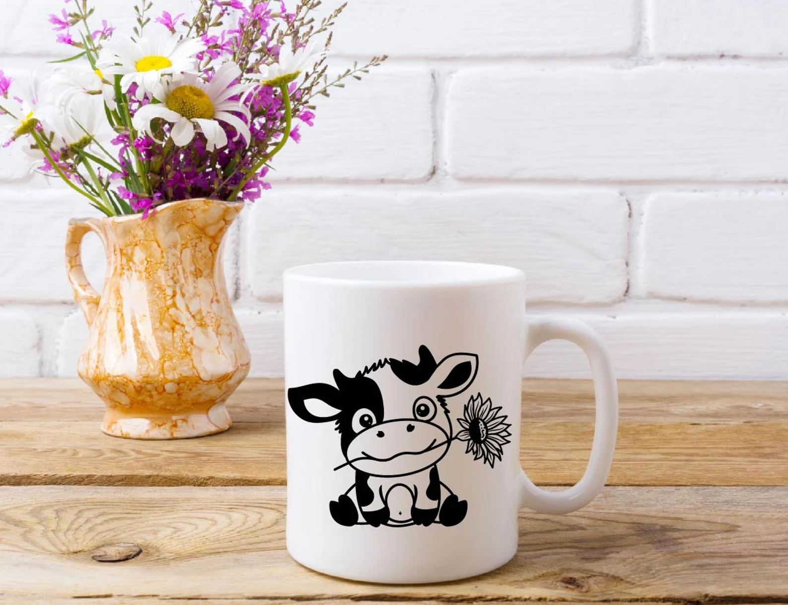 Cow mug sitting next to a vase of flowers.