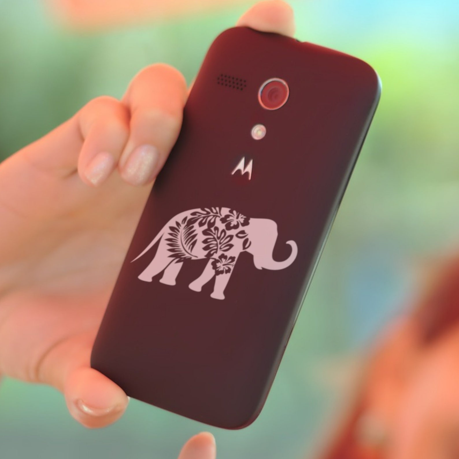 Person holding a cell phone with a picture of an elephant on it.