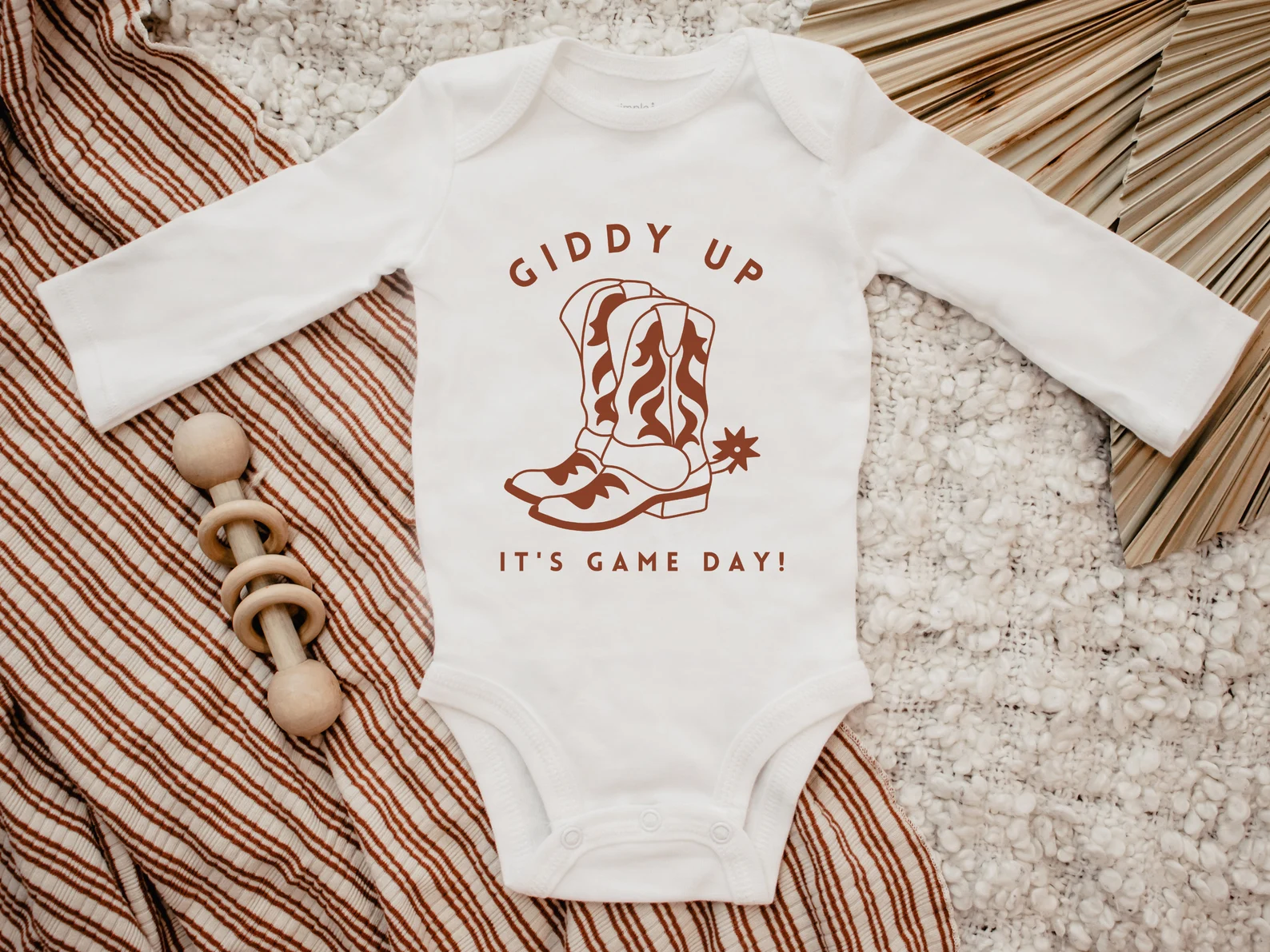 White clothes for baby with the brown cowboys illustration.
