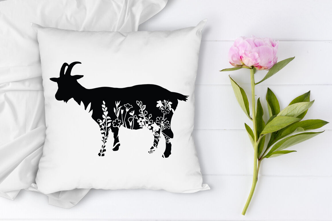 Pillow with a goat on it next to a pink flower.
