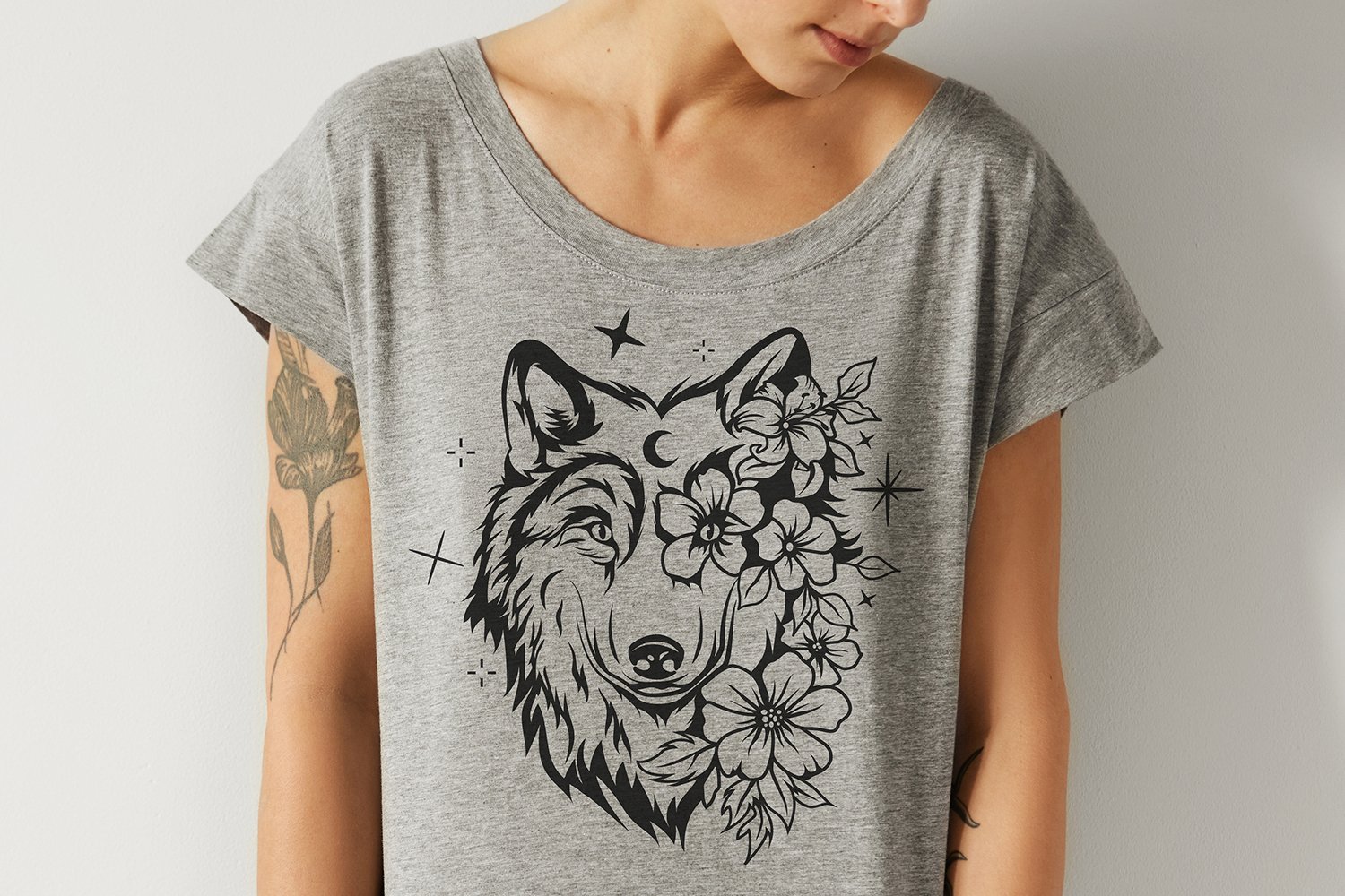 Woman wearing a grey shirt with a wolf and flowers on it.