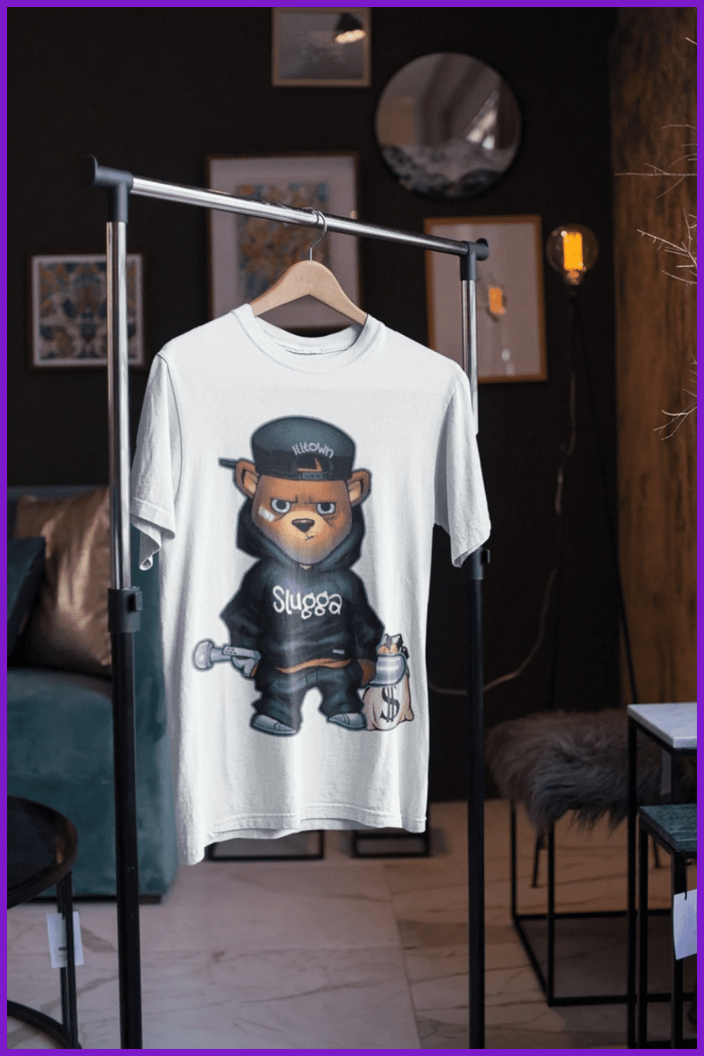 A white t-shirt with a ganster bear on it hangs on a hanger.