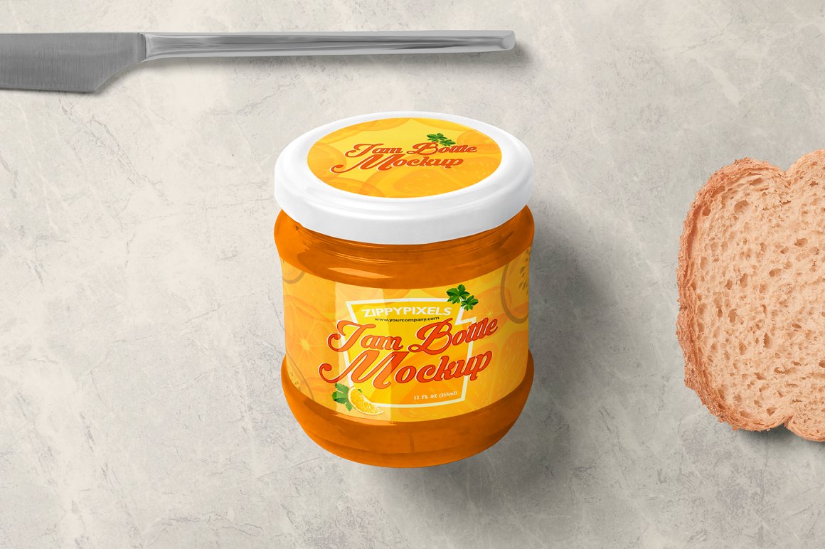 An orange glass jam jar with a white lid and an orange label with the lettering "I'm a bottle mockup", a knife and a piece of toast bread.