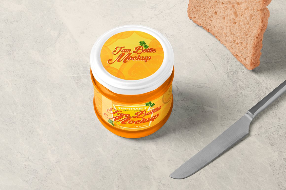 An orange glass jam jar with a white lid and an orange label with the lettering "I'm a bottle mockup", a knife and a piece of toast bread.