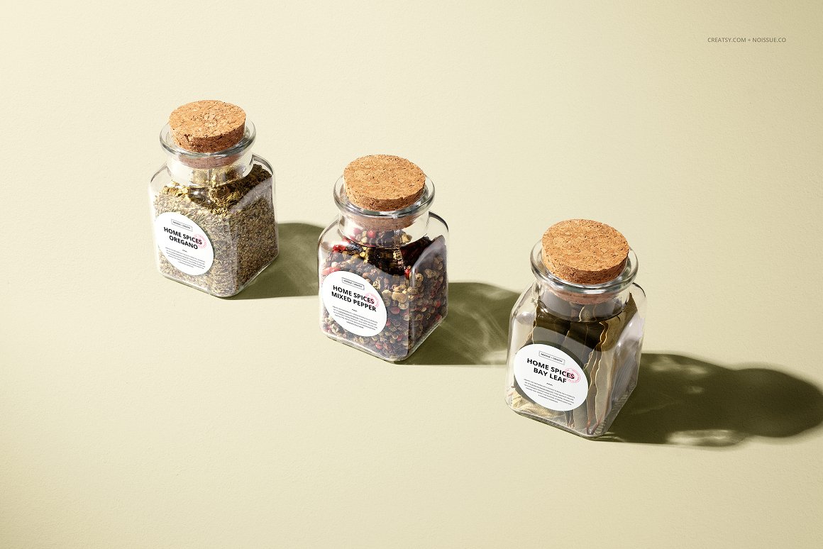 3 glass jars with different spices and white label with letterings - oregano, mixed pepper and bay leaf.