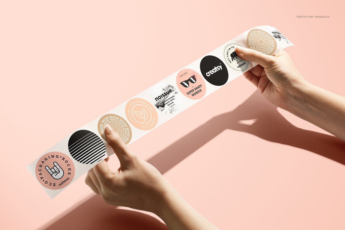 Woman's hands hold a set of 10 stickers in pink, black and beige.
