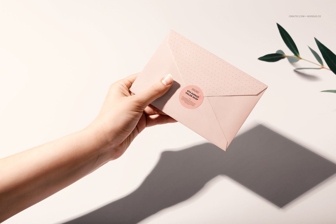 A woman's hand holds a pink envelope with a pink label and the lettering "6th avenue tailor shop".
