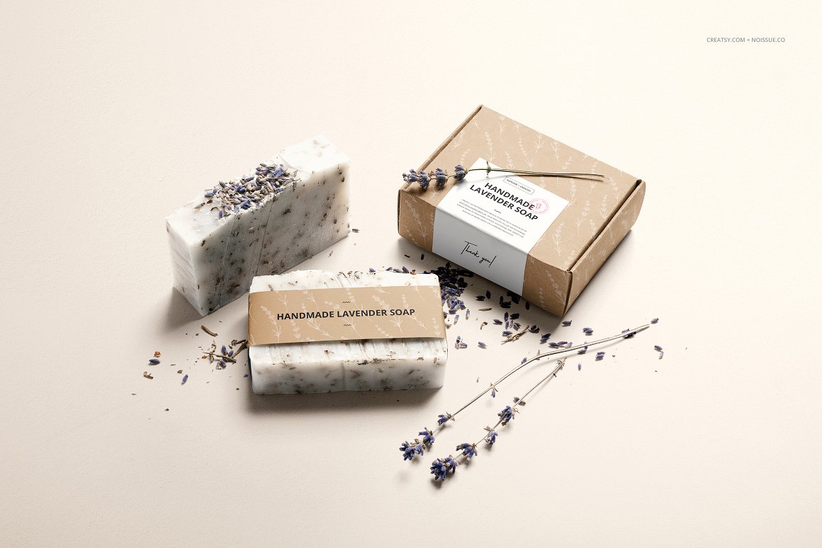 2 soaps, lavender flowers and a craft box with a white label and the lettering"Handmade Lavender Soap".
