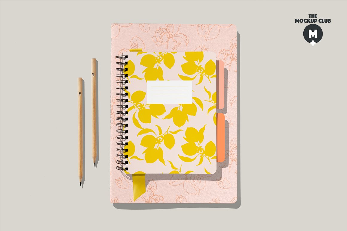 Pink spiral notebook mockup with lemon images, 2 beige pencils and pink notebook A4 mockup with fruit print on gray background.