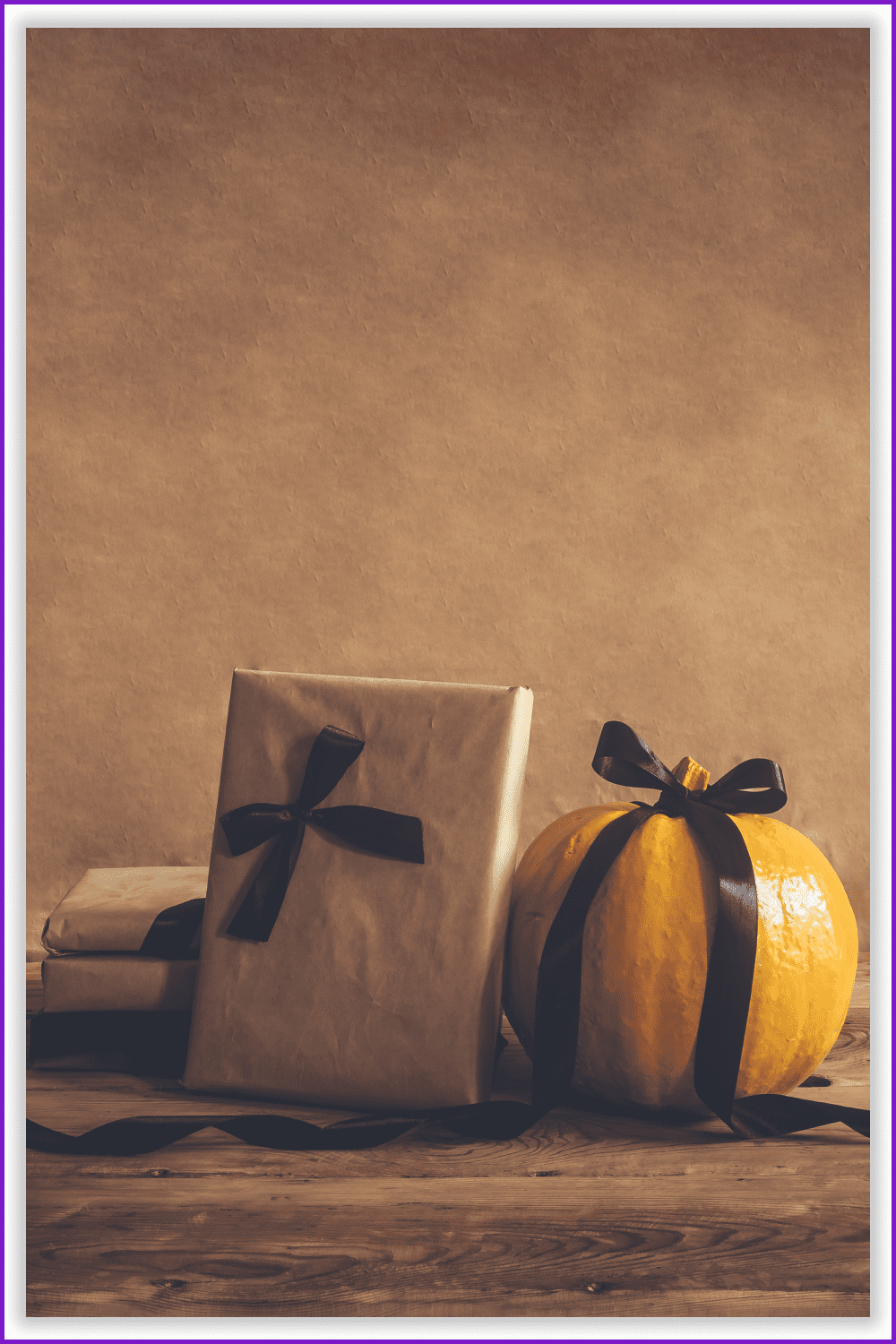 Photo of a yellow pumpkin and a gift wrapped in paper against a brown wall.
