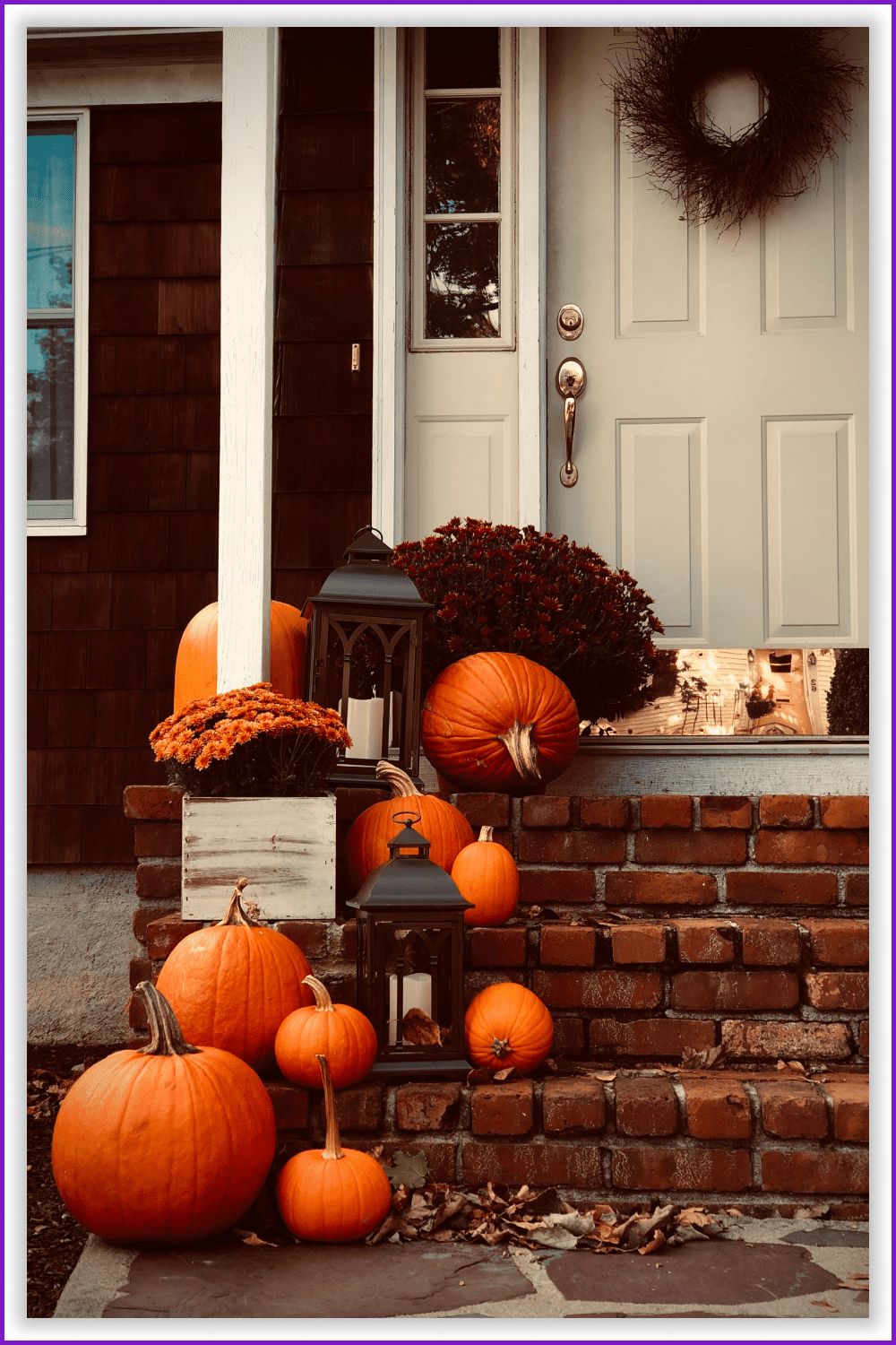 Photo of a house porch with orange pumpkins and big lanterns on it.