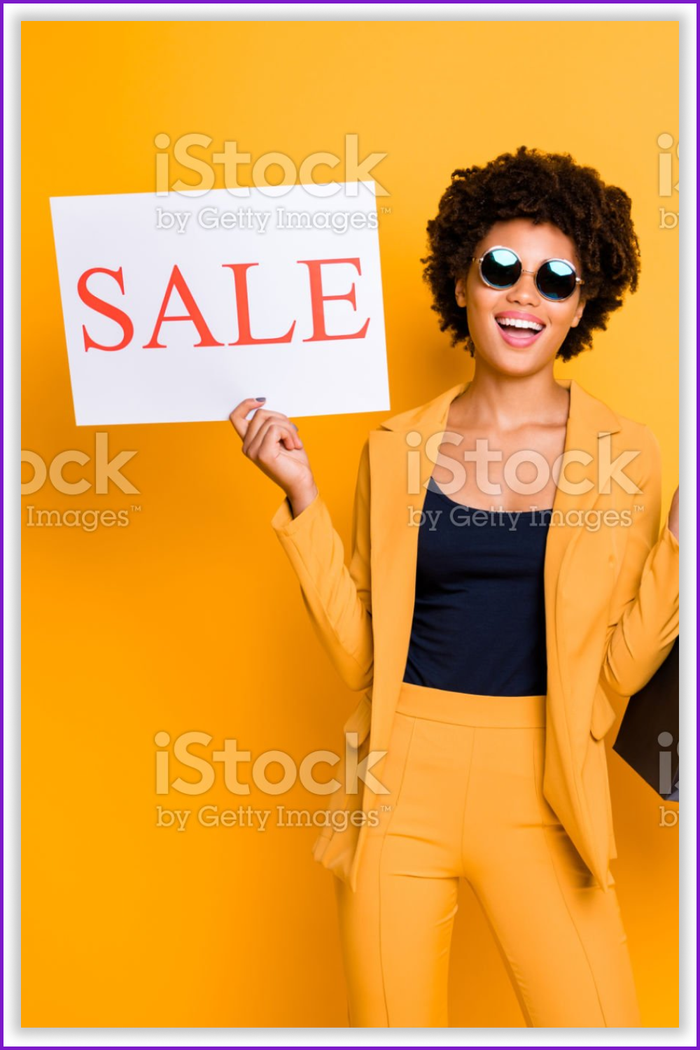 Woman in yellow with sign “Sale” on the bright orange background.