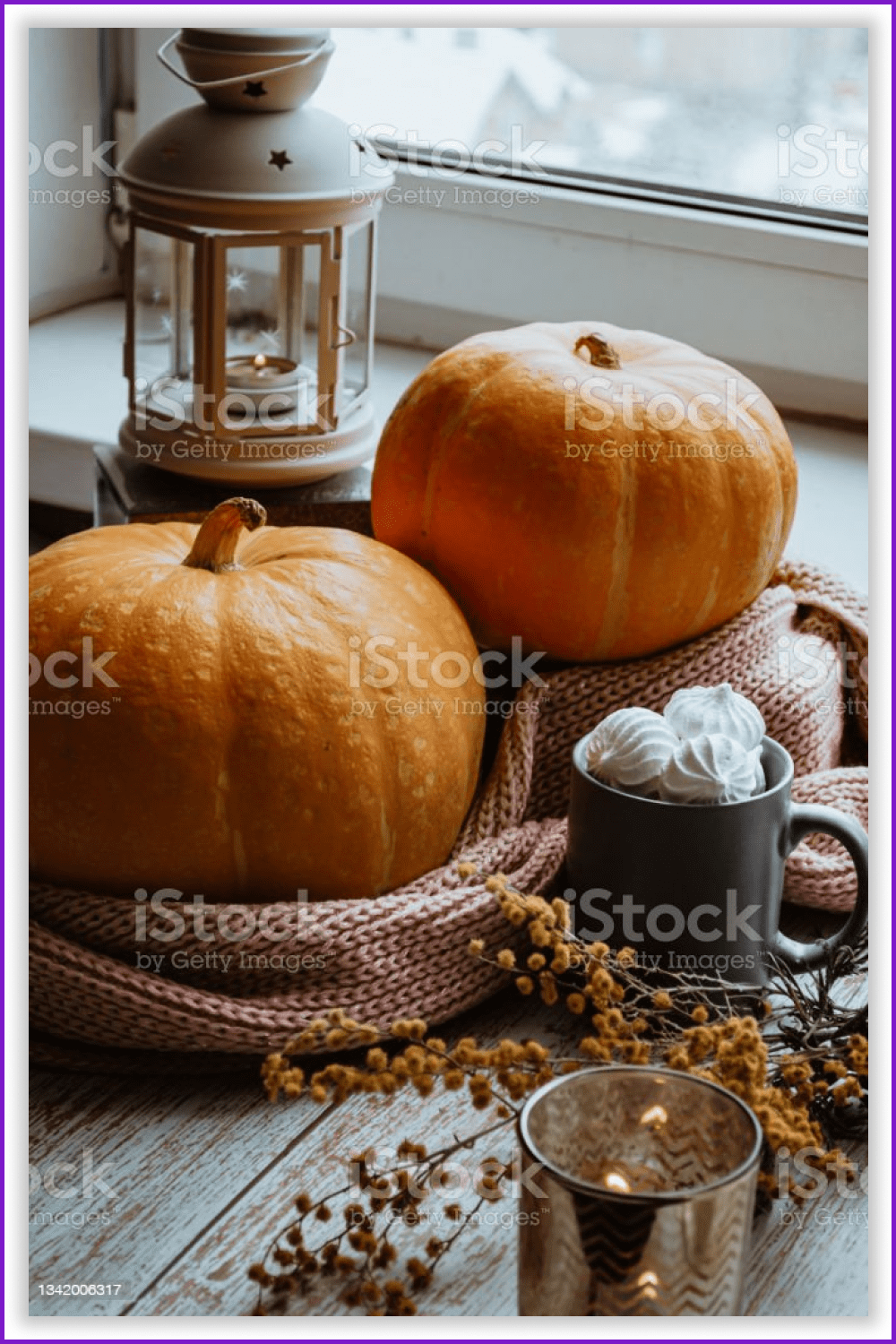Orange pumpkins with cups, candlesticks and a scarf on the table.