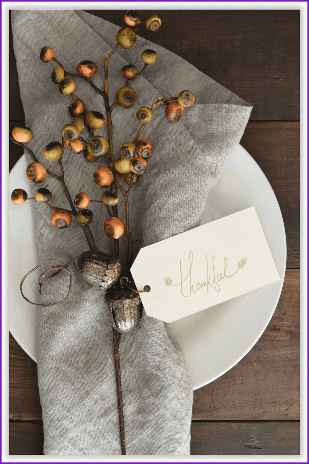 A table serving with a “Thankful” tag, a napkin, and decorative oak branches on top.