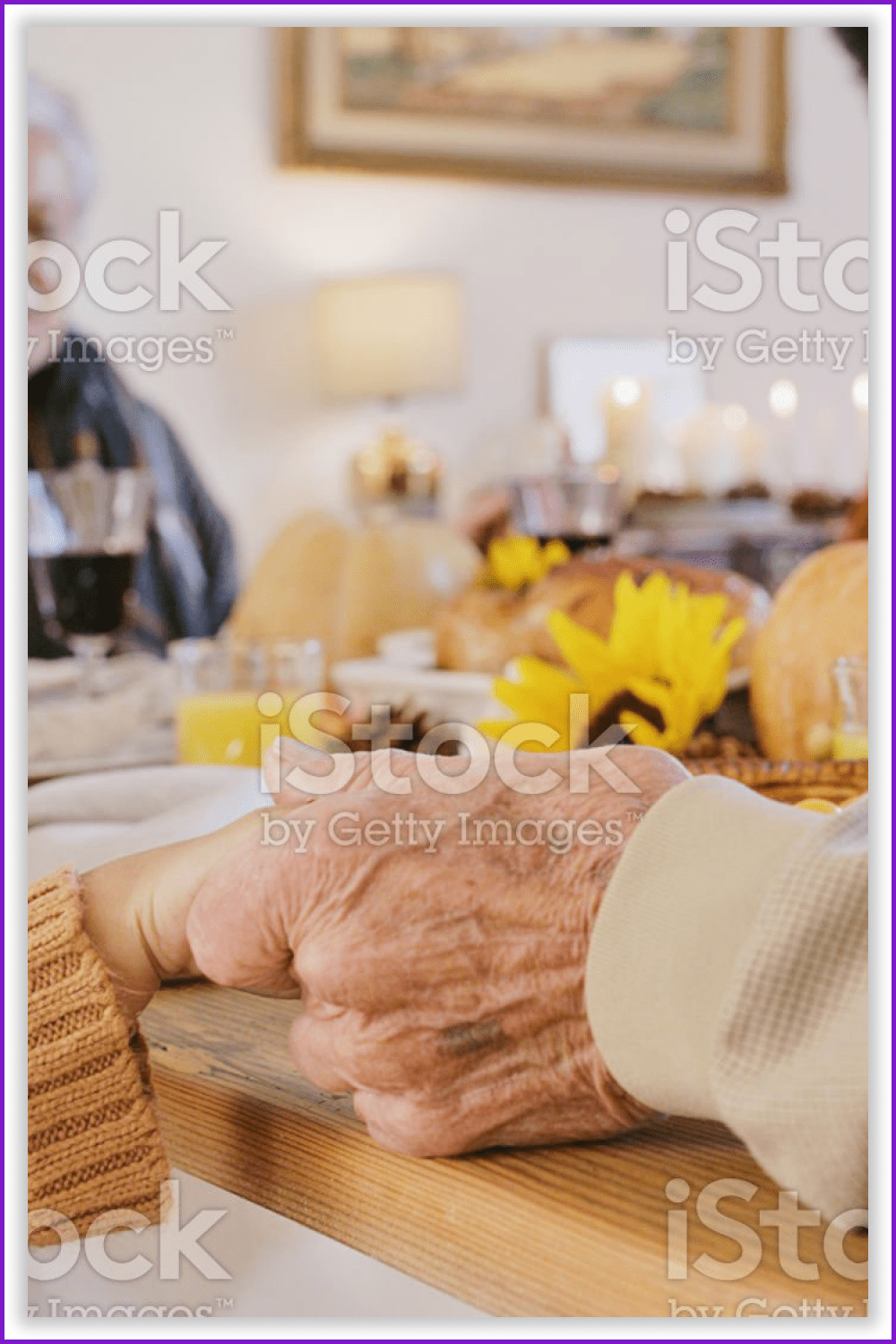Grandmother's hand holding granddaughter's hand while praying during thanksgiving dinner.