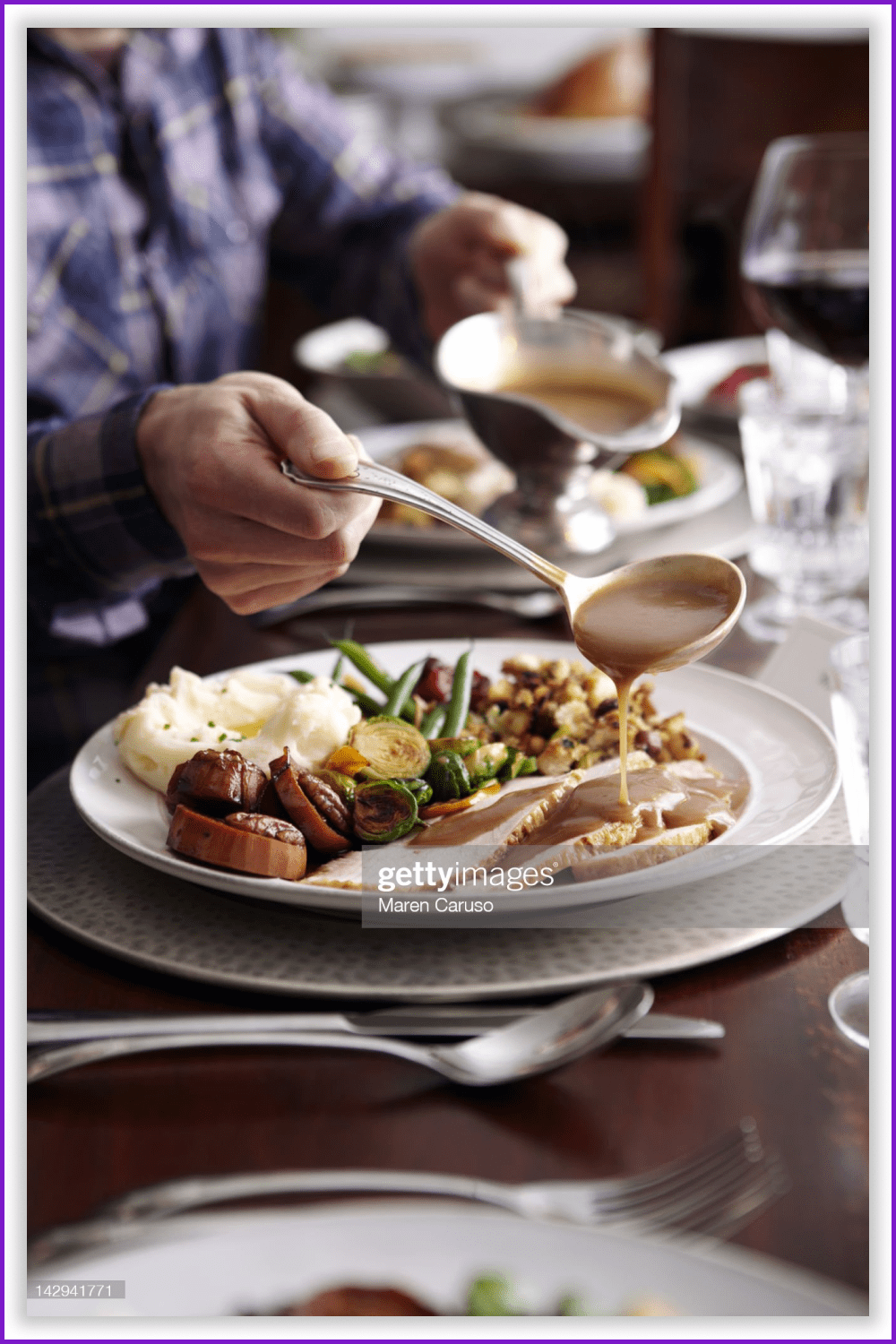 A man pouring gravy sauce onto his Thanksgiving meal.