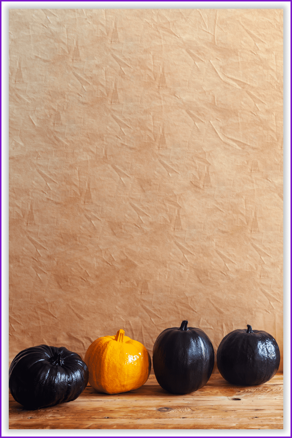 Three black and one yellow pumpkins on a brown background.
