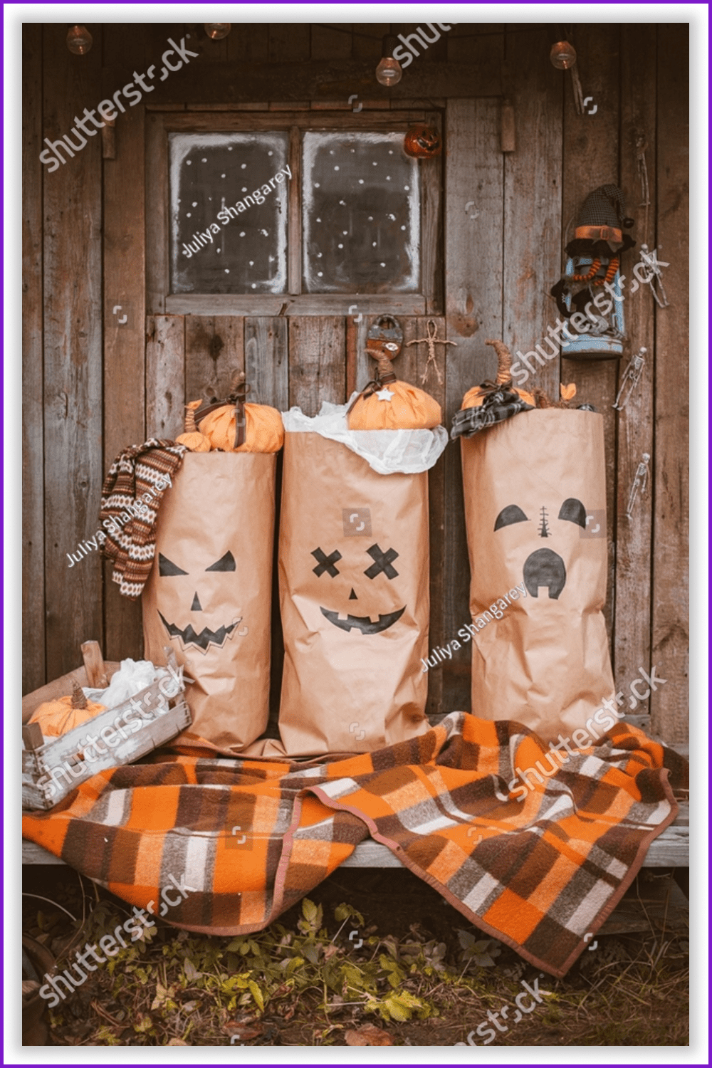 Photo zone with a bench with a checkered blanket, paper bags with pumpkins against the background of a wooden house.