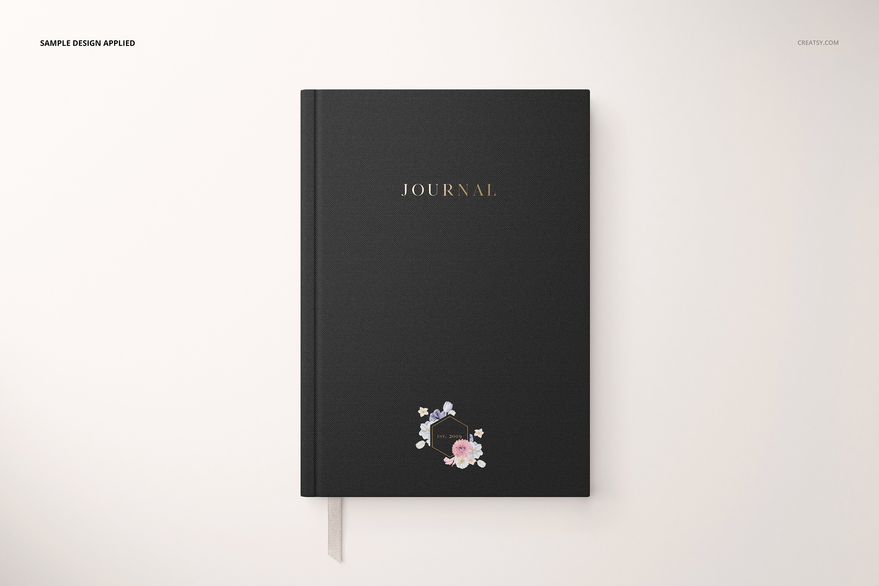 Matte black notebook with a gold font and some flowers logo.