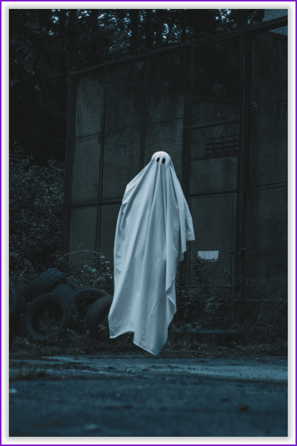 Photo of a tall man in a white sheet in the industrial area.