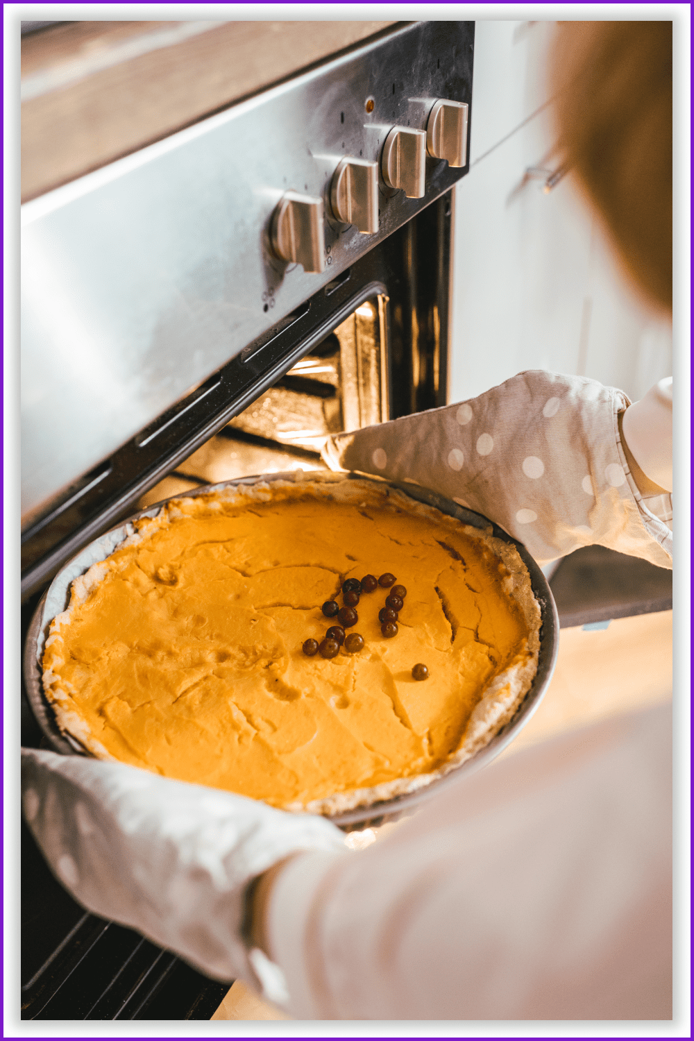Woman in kitchen gloves taking a pumpkin pie out of the oven.