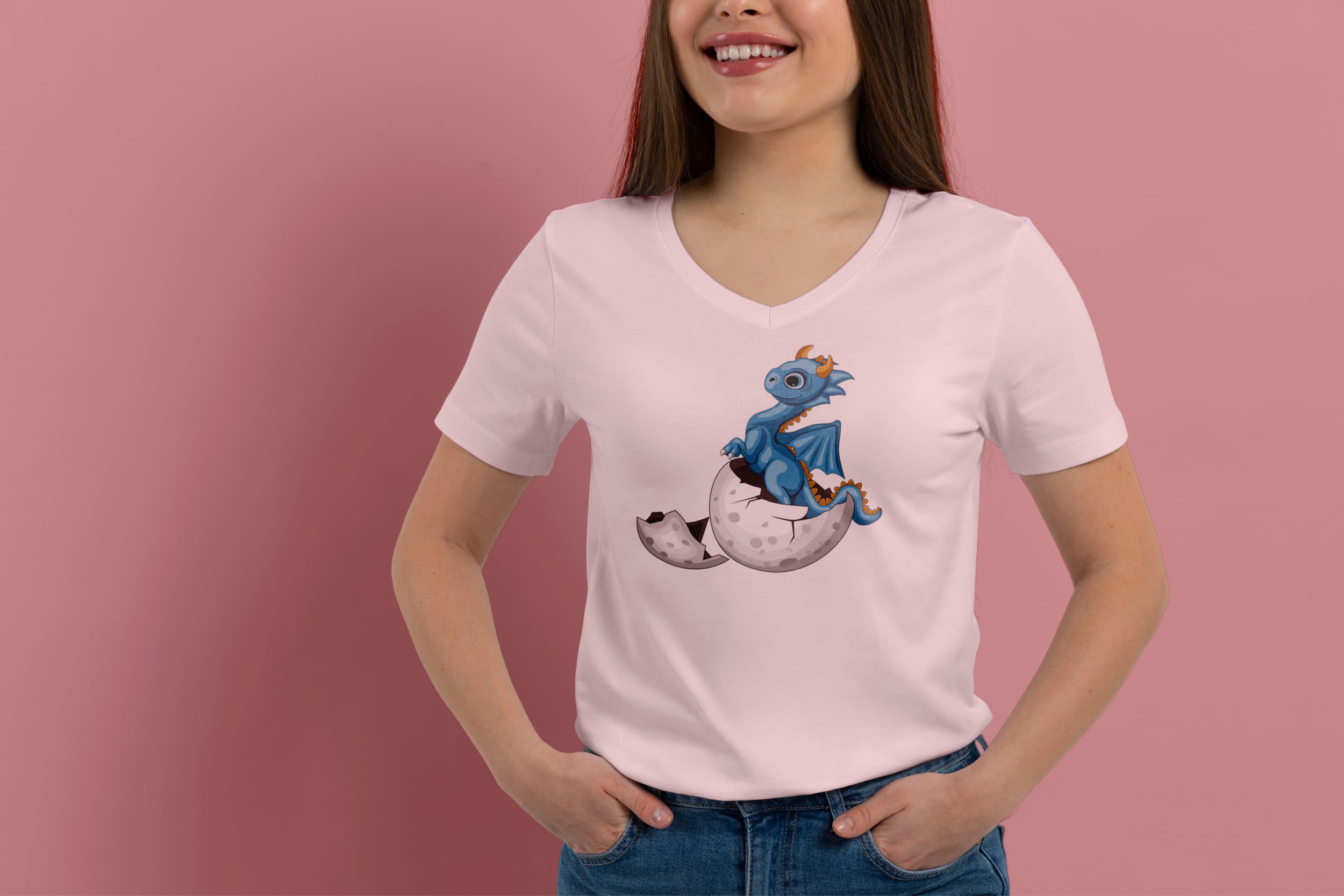 A light pink t-shirt on a girl with a light blue dragon hatched from an egg, on a pink background.