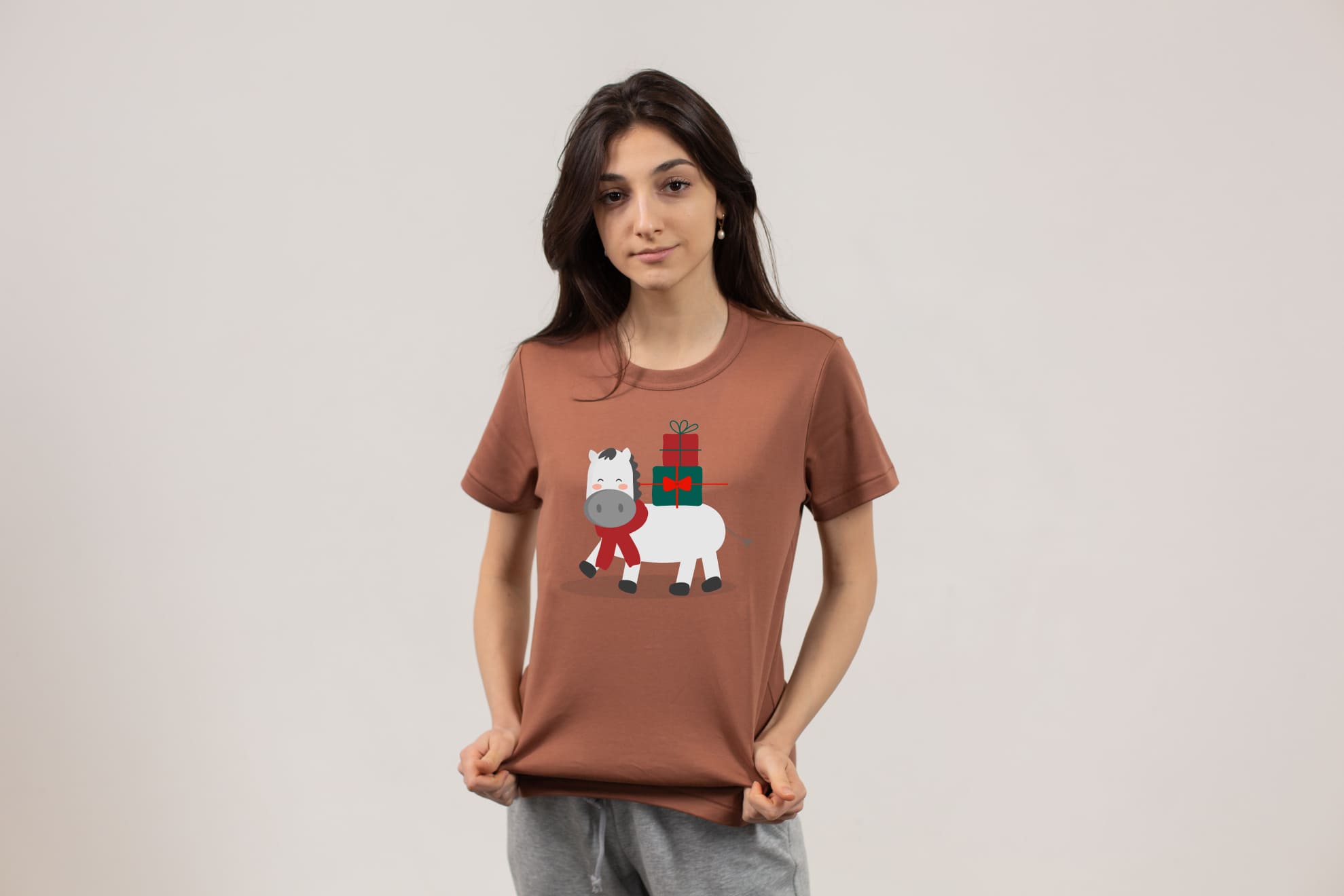Brown t-shirt with a christmas horse on a girl on a gray background,