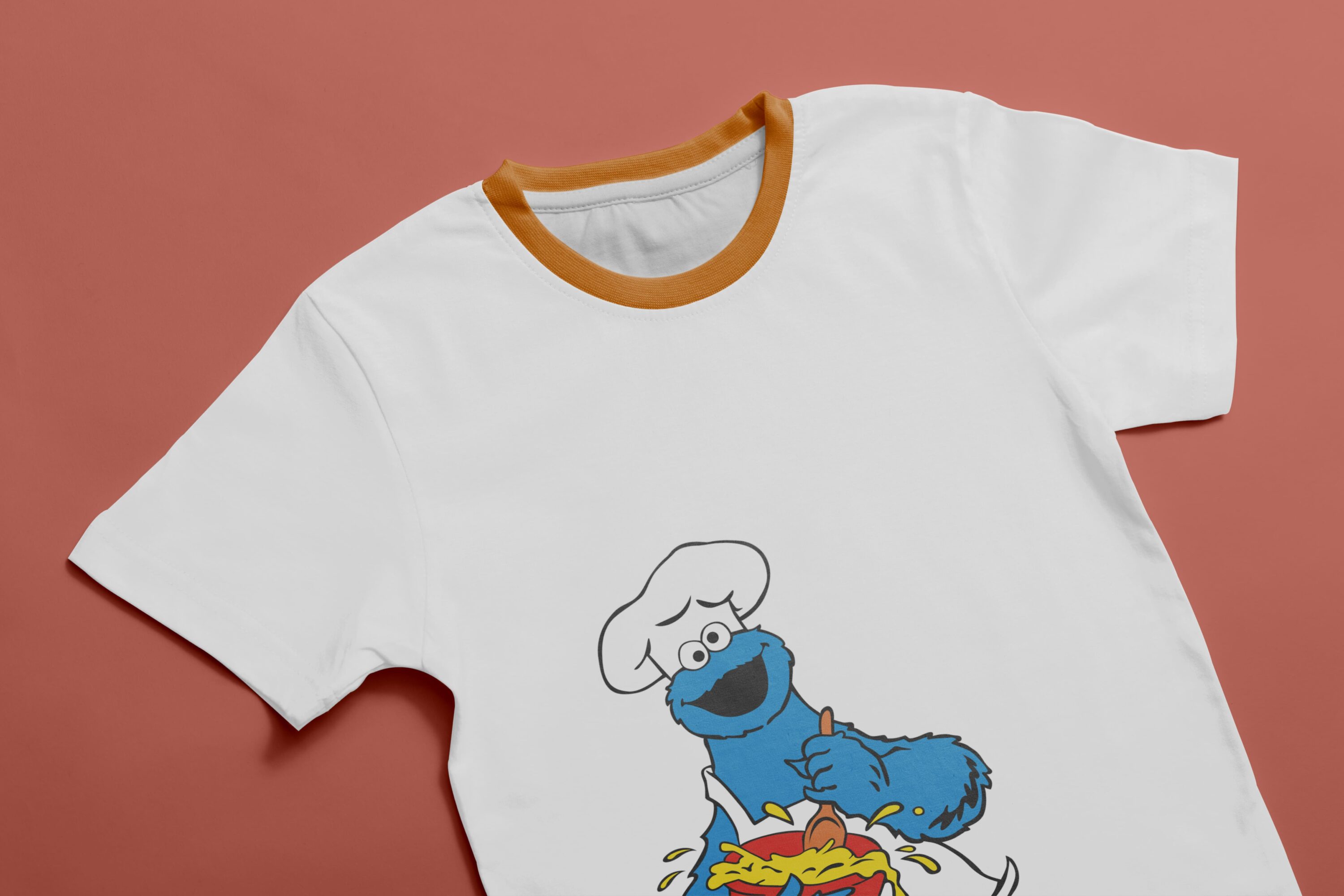White T-shirt with orange collar and an image of a character - Cookie Monster, who cooks food.