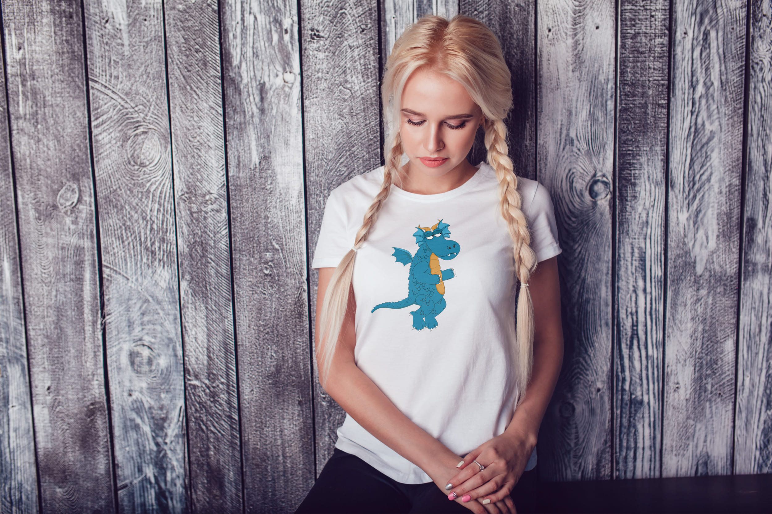 A girl with blond hair and a white T-shirt with a turquoise dragon.