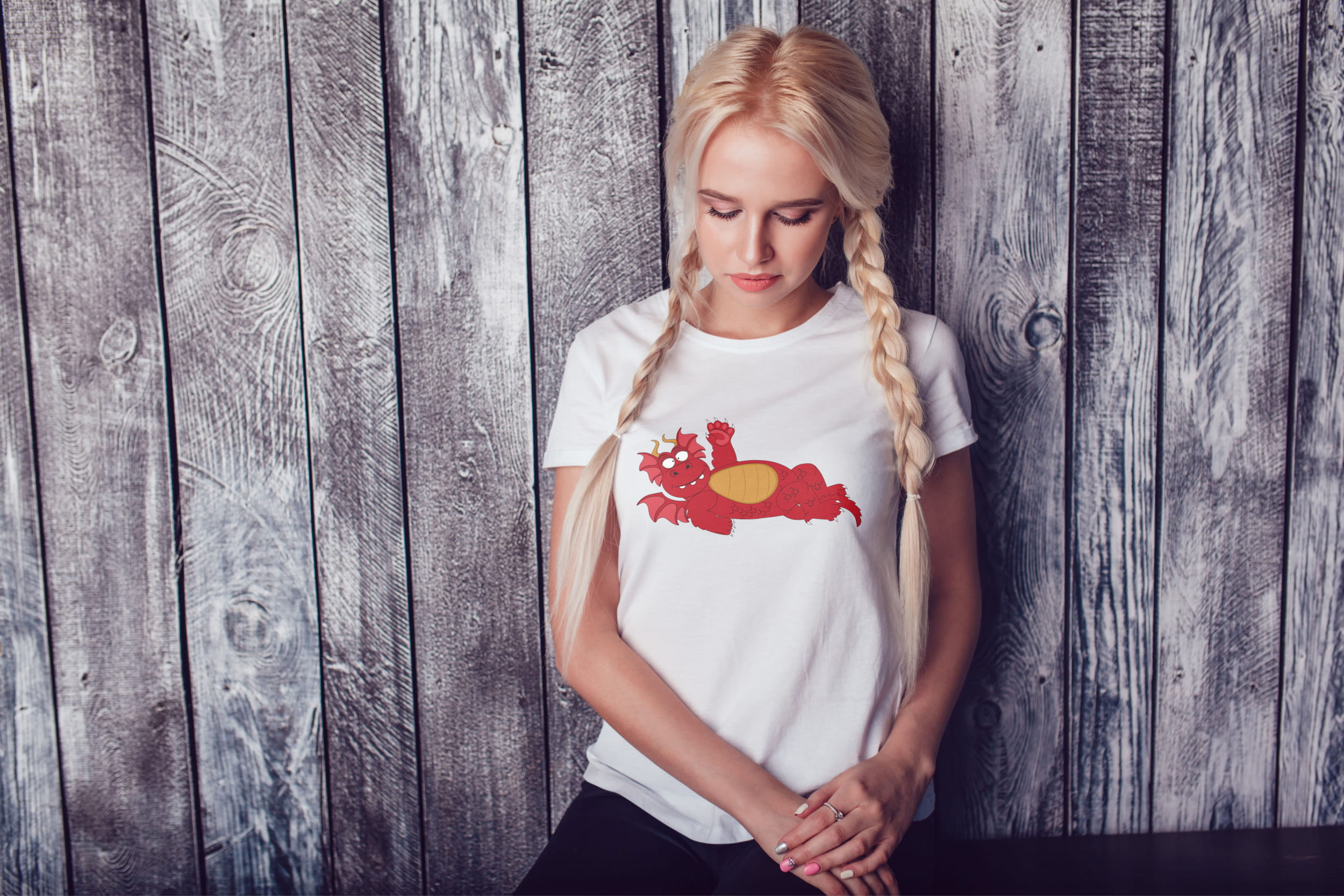 A girl with blond hair and a white T-shirt with a red dragon.