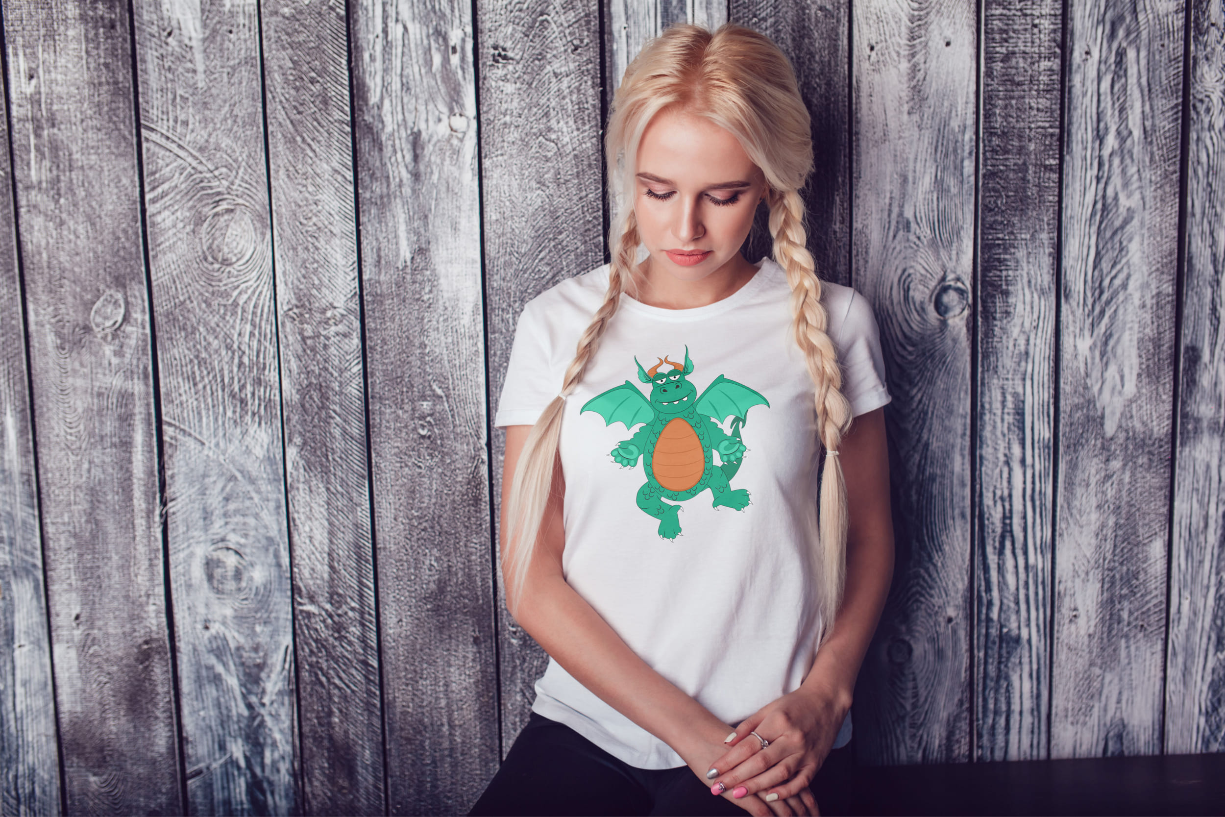 A girl with blond hair and a white T-shirt with a green dragon.