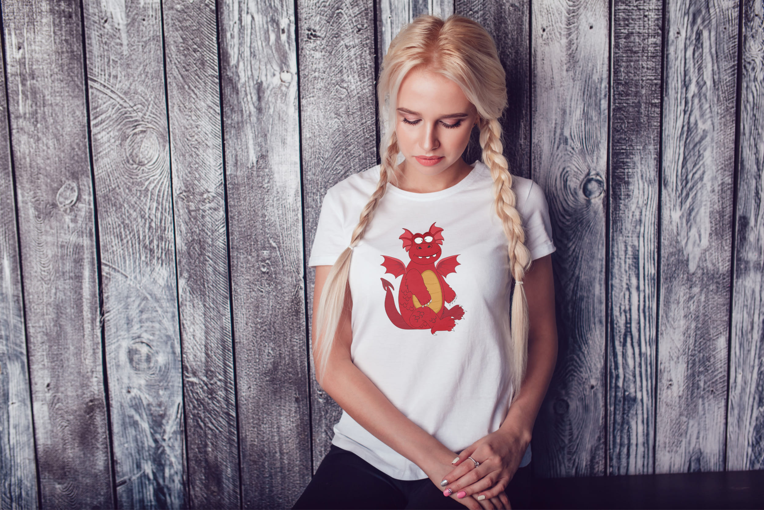 A girl with blond hair and a white T-shirt with a red and orange dragon.